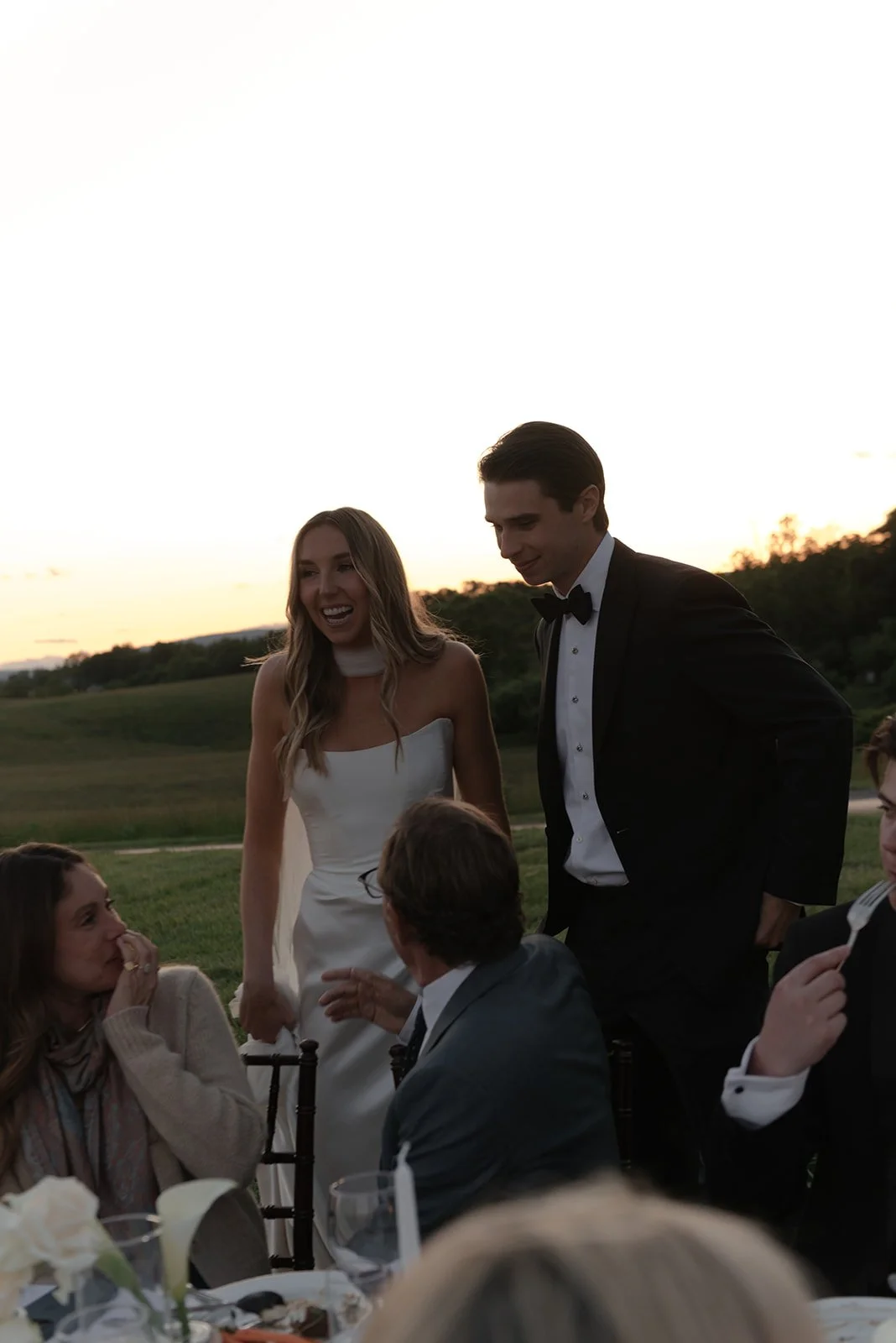 Bride and groom visit tables during their al fresco wedding reception in the Hayfield