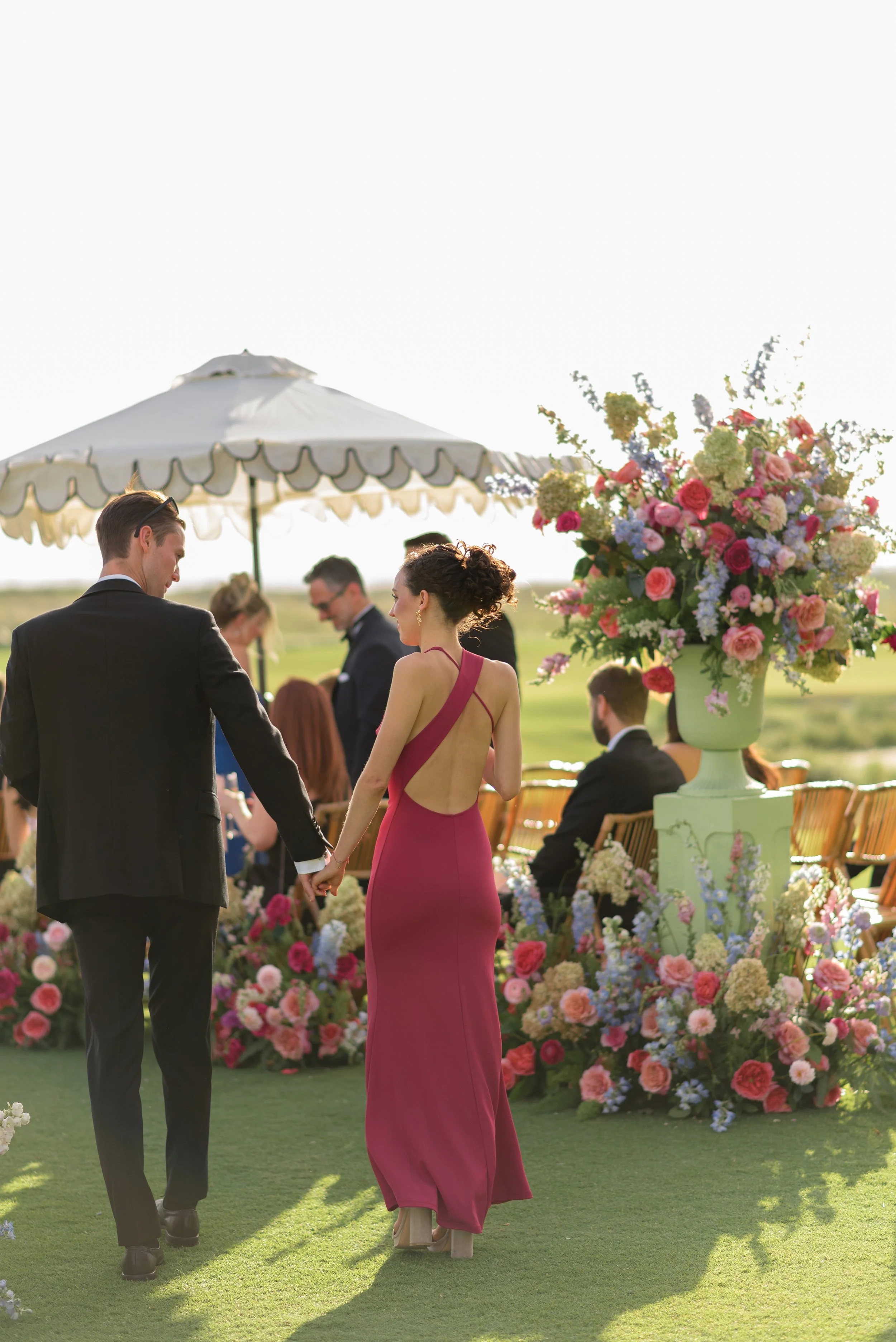 Wedding party members walk down the flower-lined aisle during Katie and Trevor’s Ocean Course ceremony.
