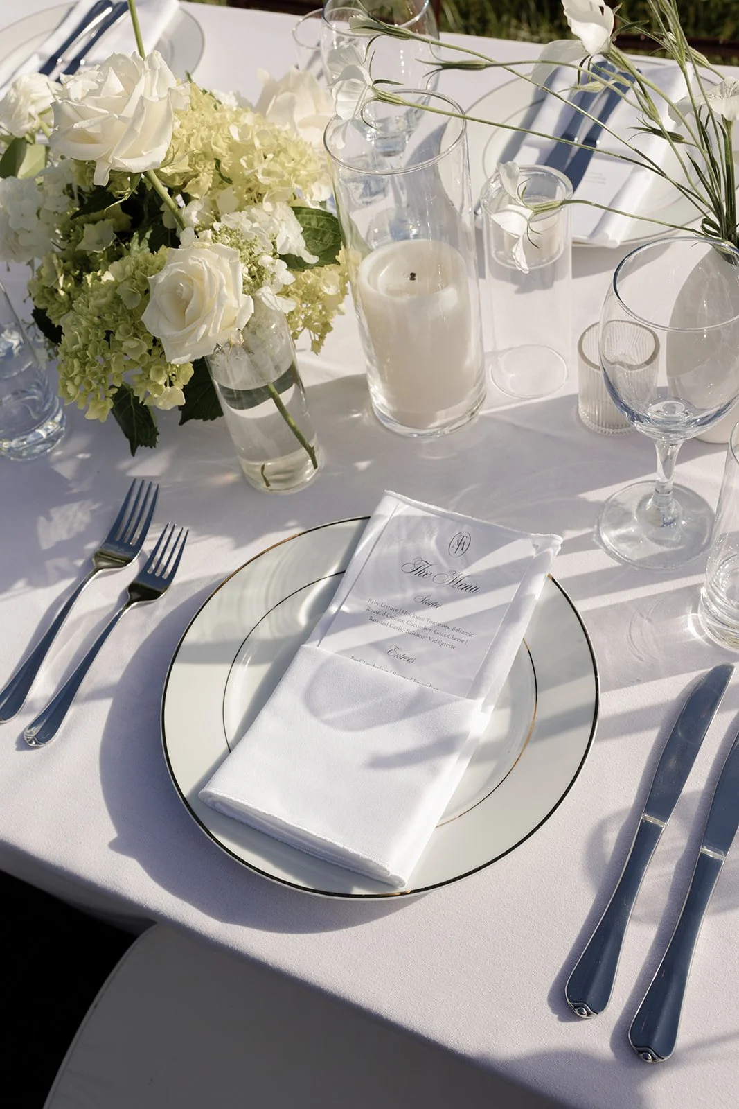 Outdoor wedding place setting with white linens, glassware, ivory flowers, and pale green details at Goodstone Inn.