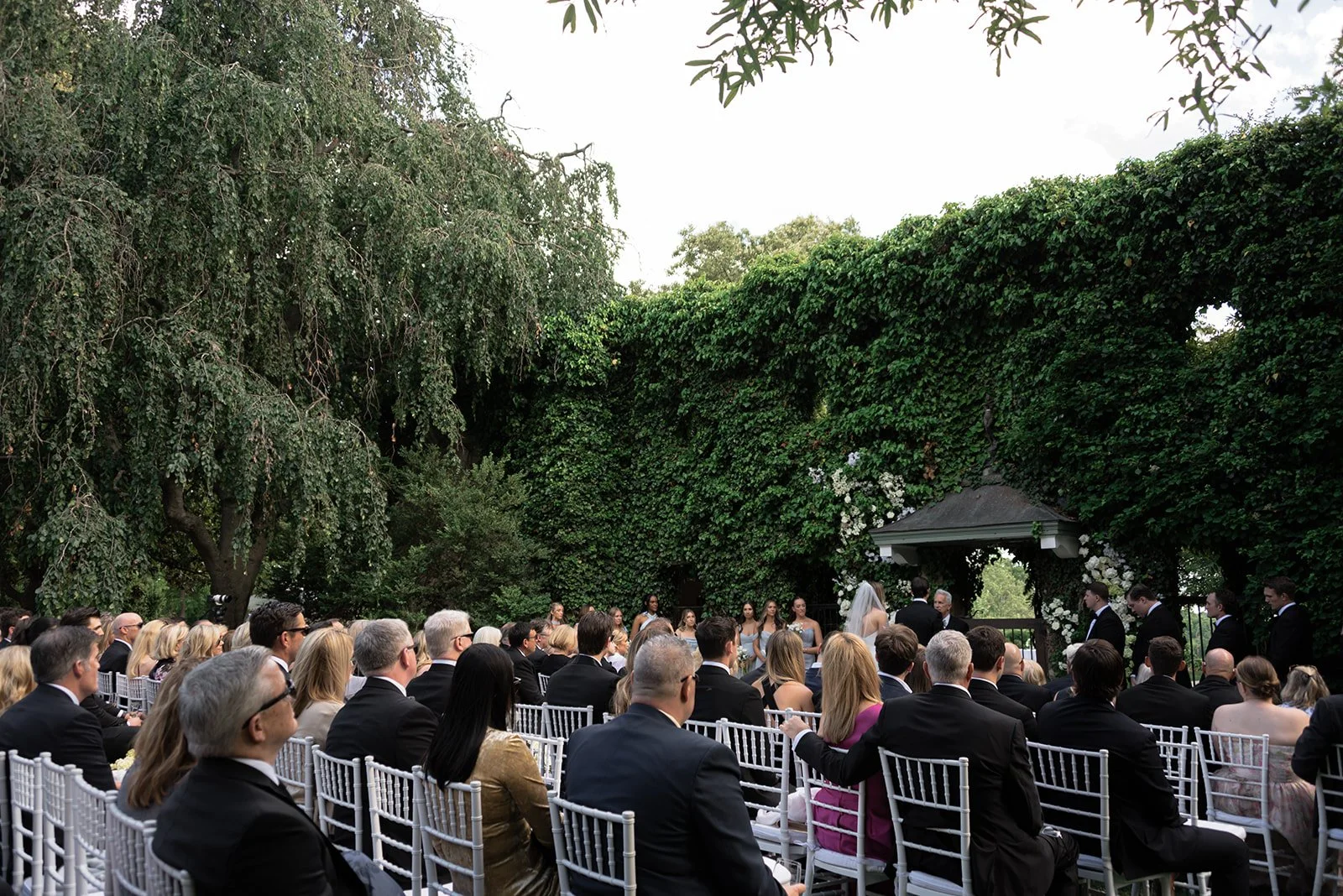 Outdoor ceremony guests seated beneath greenery at the Ivy Wall at Goodstone Inn.