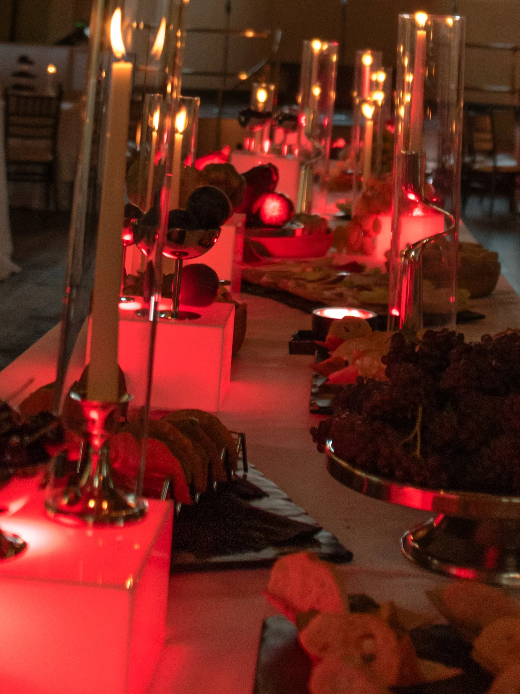 Close view of the red-lit food and candle display designed for the rehearsal dinner.