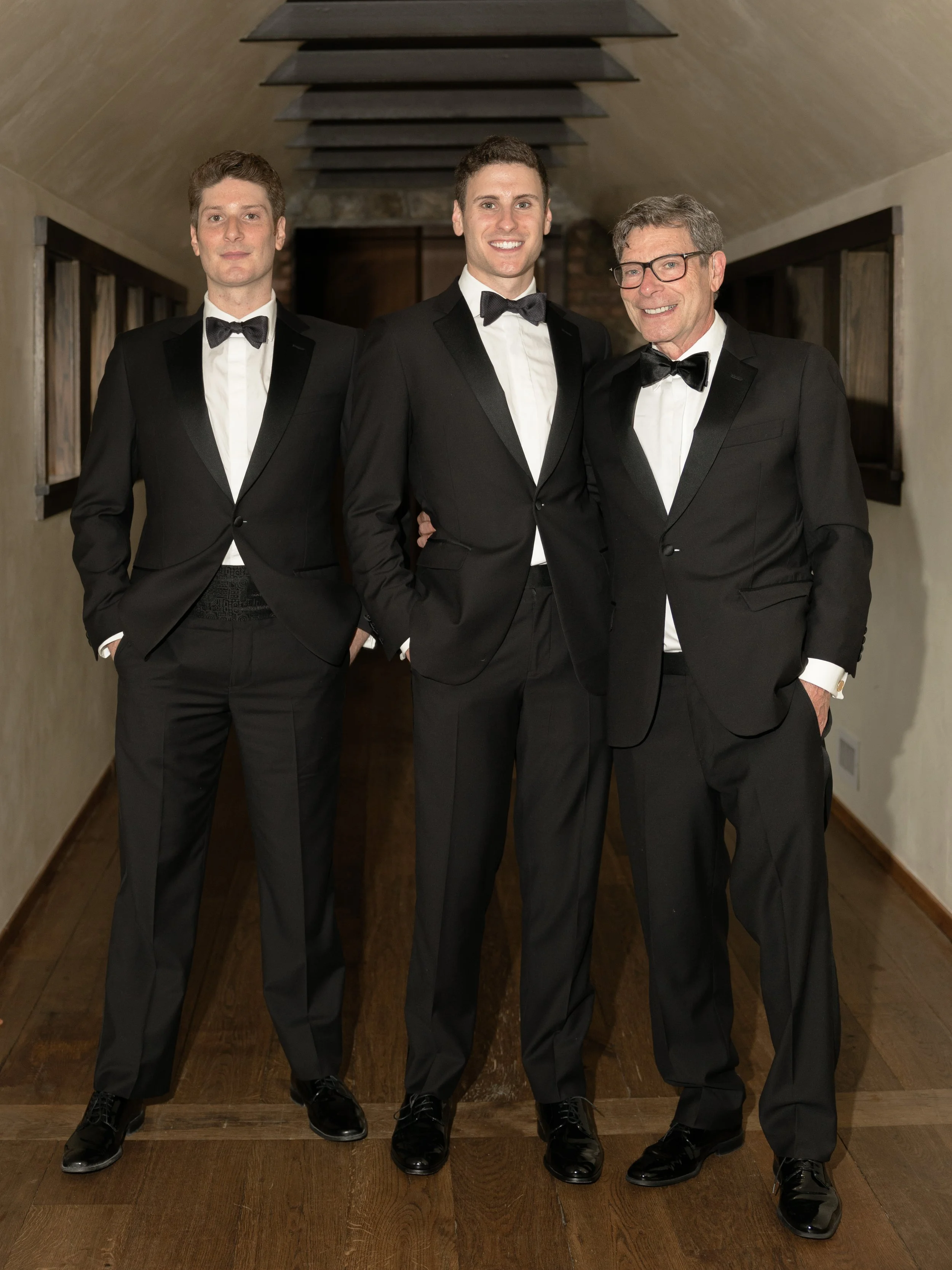 The groom, his father, and brother pose for portraits during a black-tie Hudson Valley wedding celebration.