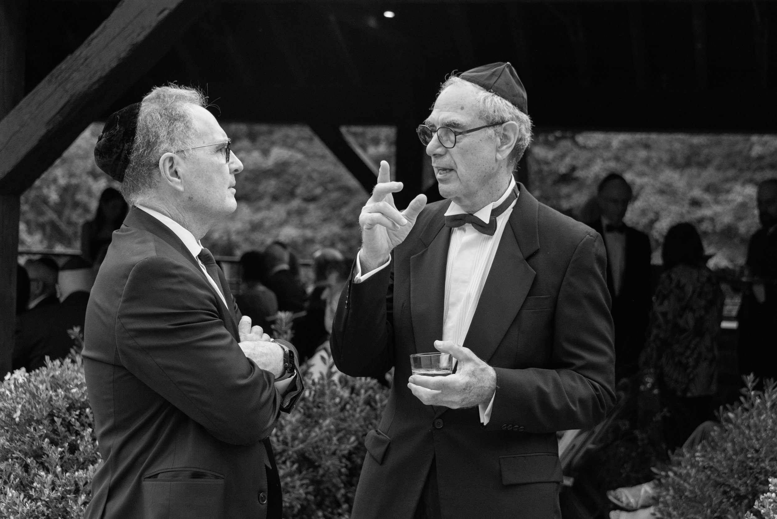 Two Jewish wedding guests wearing yamakas have a discussion before the ceremony.  