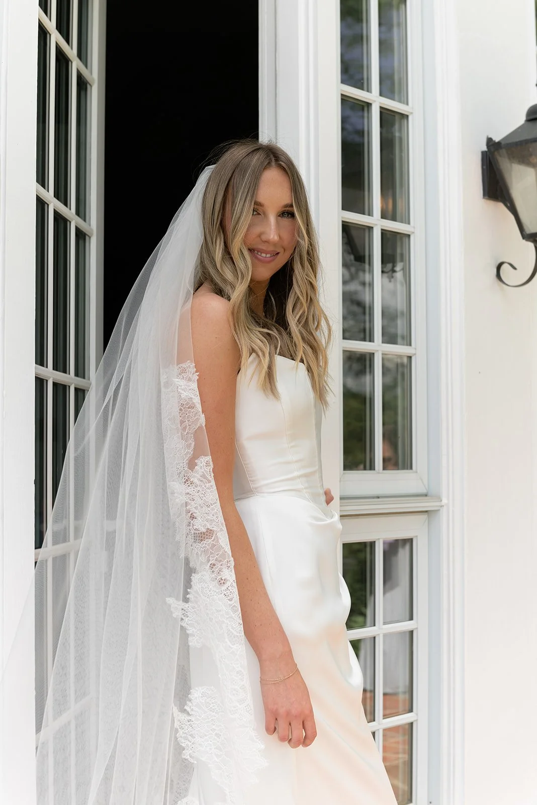 Bride standing outside the Manor House at Goodstone Inn in a sleek white Tara Lauren wedding gown.
