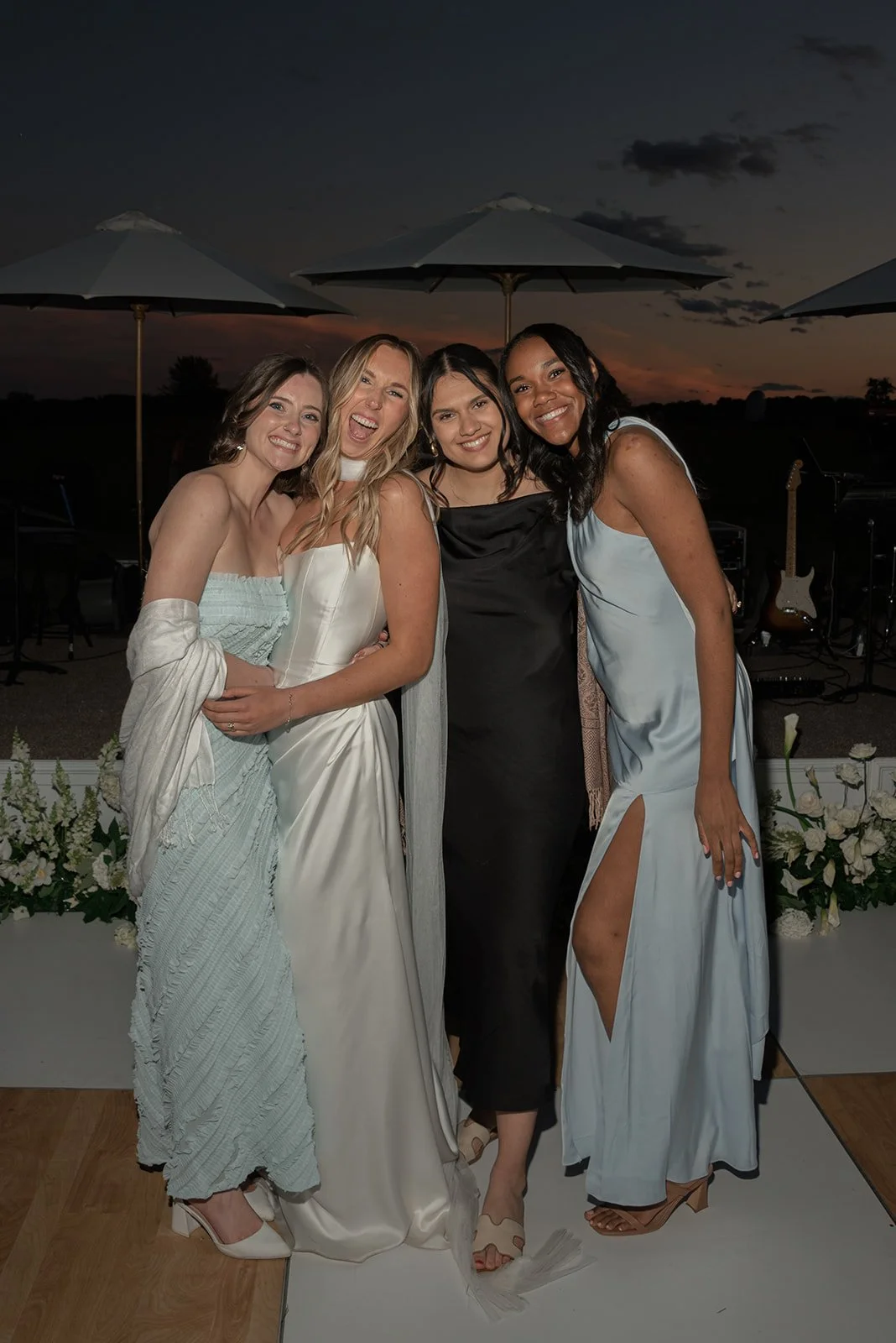 Bridesmaids in pale blue dresses standing together during the reception on the checkerboard dance floor.