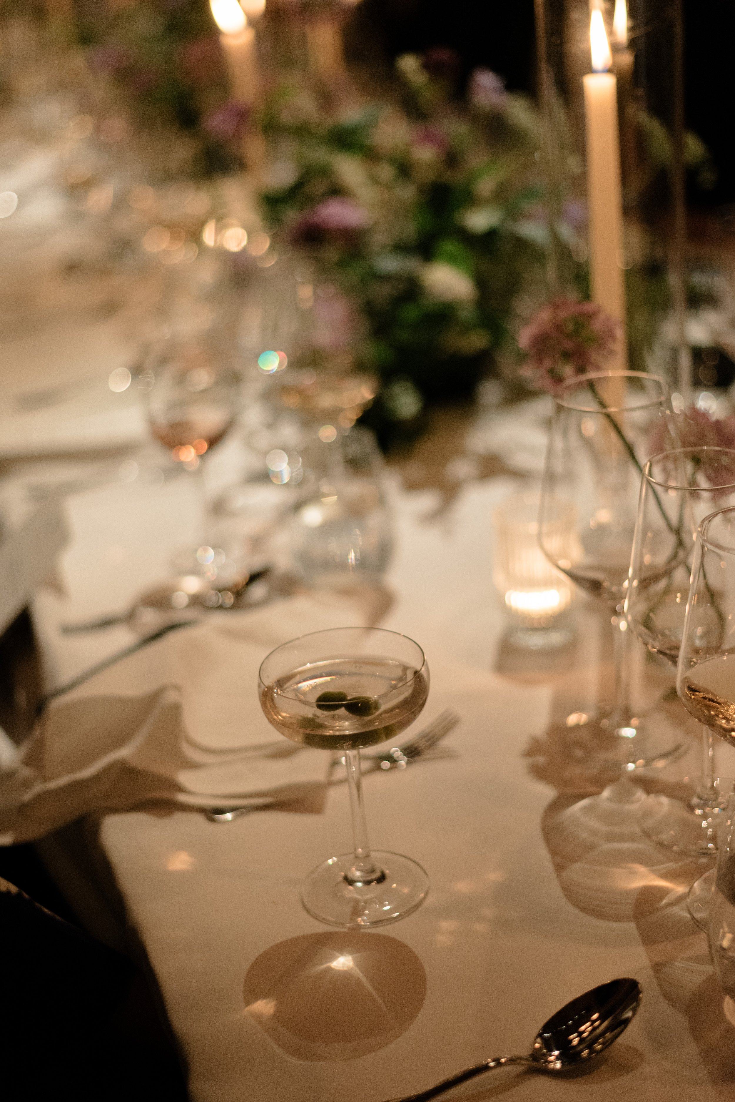 Soft candlelit detail of glassware and place settings during the Blue Hill wedding dinner.