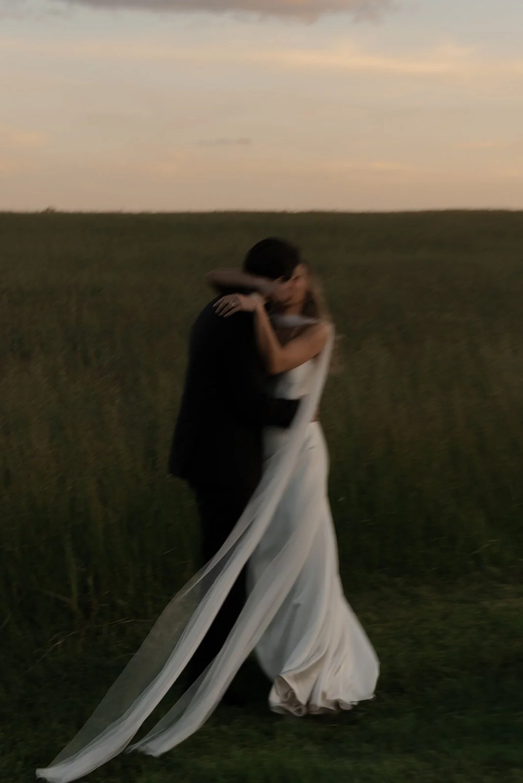 Intentional motion-blur detail of a bride and groom embracing in the Hayfield at Goodstone Inn.