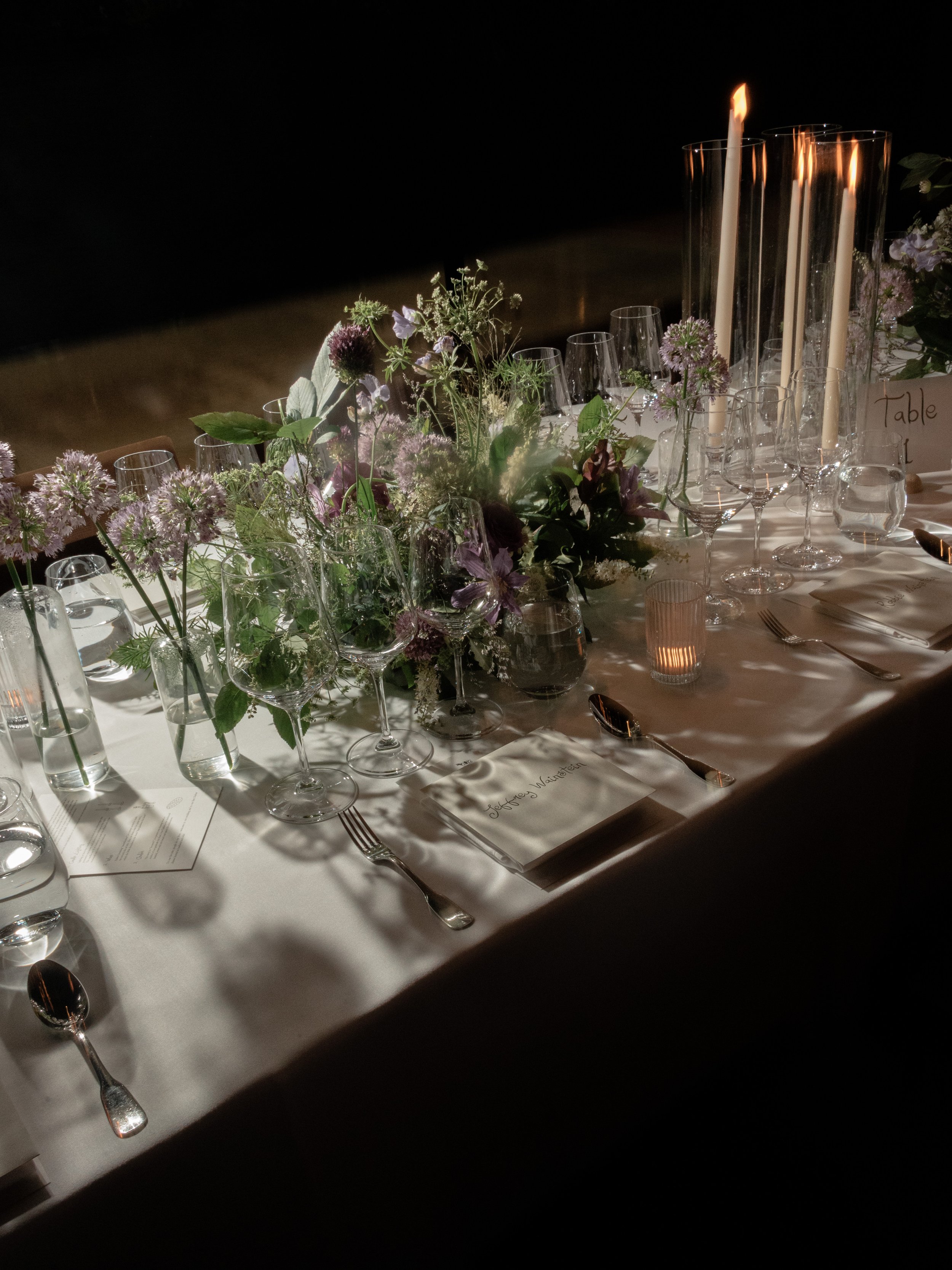 Dramatic lighting photo of organic floral arrangements designed by Wild and Birch and candlelight designed by Mudari Creative for the wedding dinner.