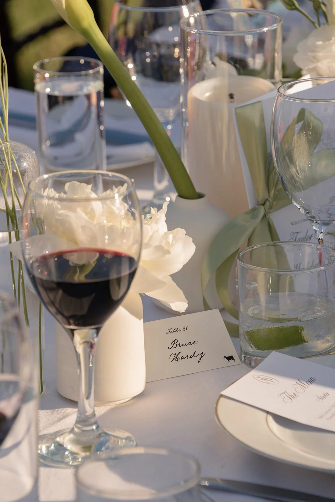 Clear glassware, candlelight, white flowers, and paper details layered on an outdoor wedding table at Goodstone Inn.