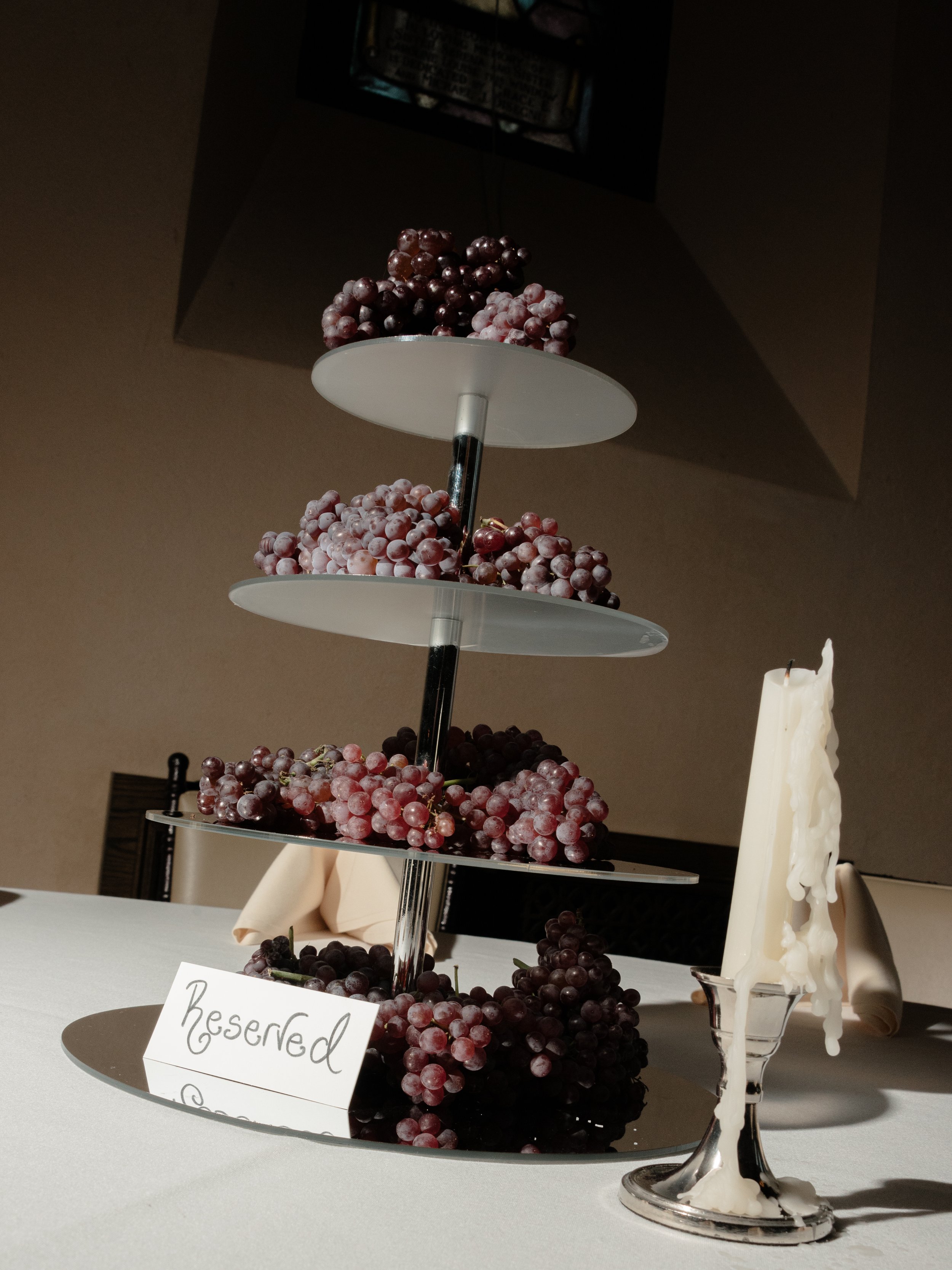 Tiered cake display topped with fresh fruit at the rehearsal dinner with a curlicue font "Reserved" sign. 