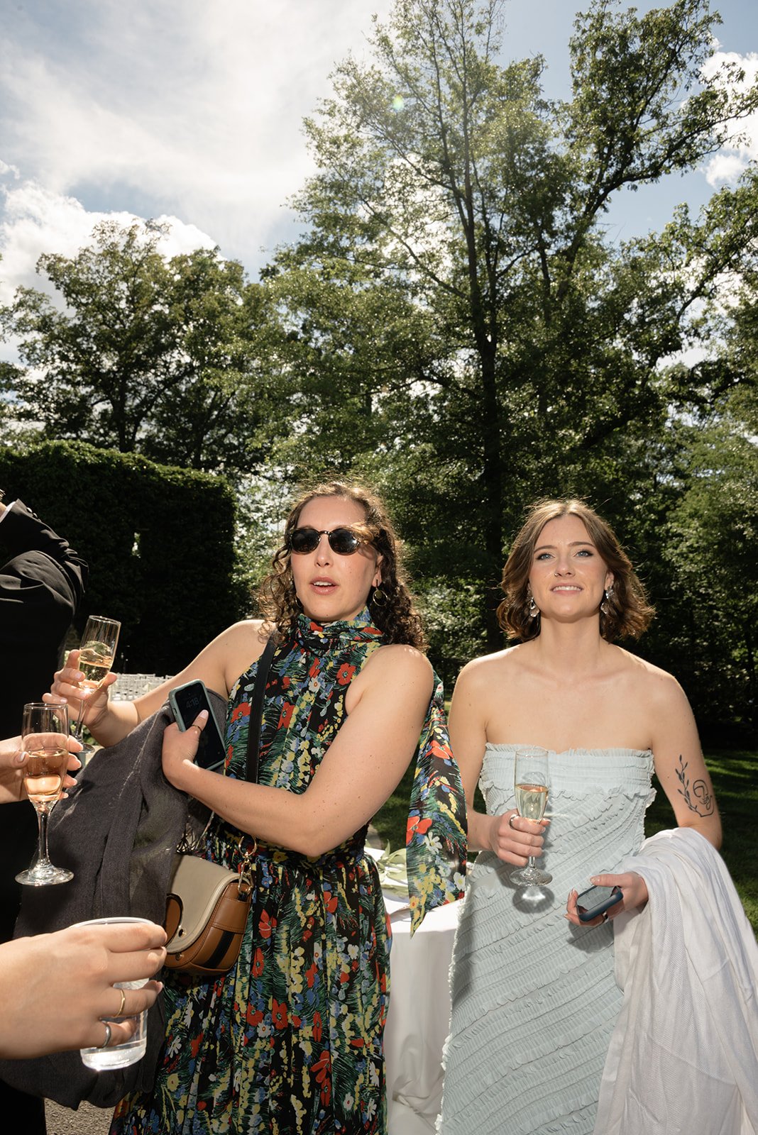 Two wedding guests in colorful dresses smiling together outdoors at Goodstone Inn.