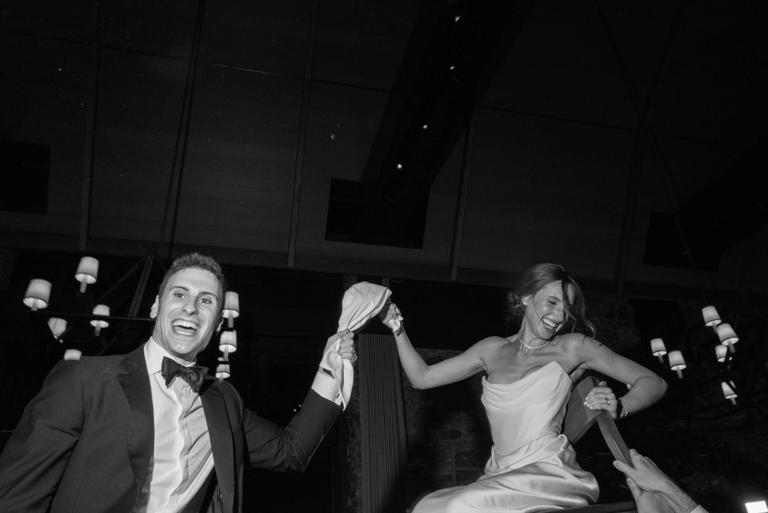 The bride and groom are lifted onto chairs during the Hora at their wedding reception.