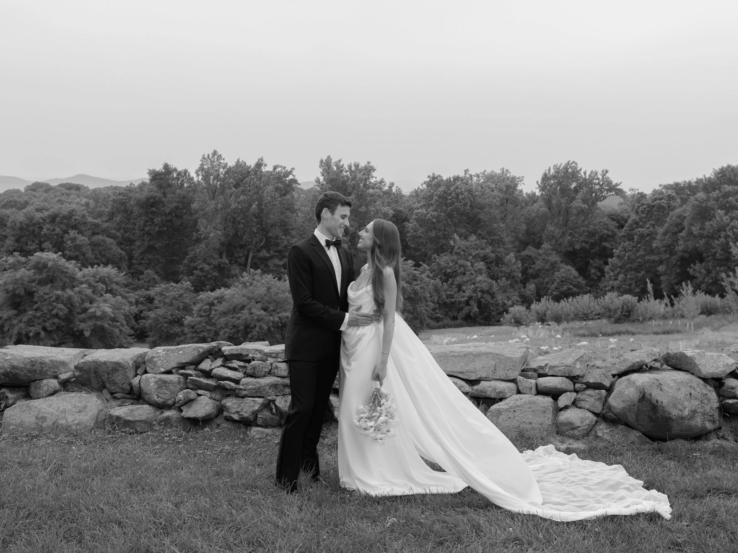 The bride and groom pose for a timeless editorial black and white portrait in the fields of the Hudson Valley behind Blue Hill at Stone Barns with the sheep in the background.