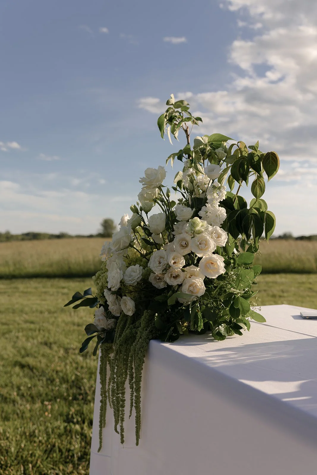 Lush ivory and green wedding centerpiece arranged at the end of an outdoor bar at Goodstone Inn.