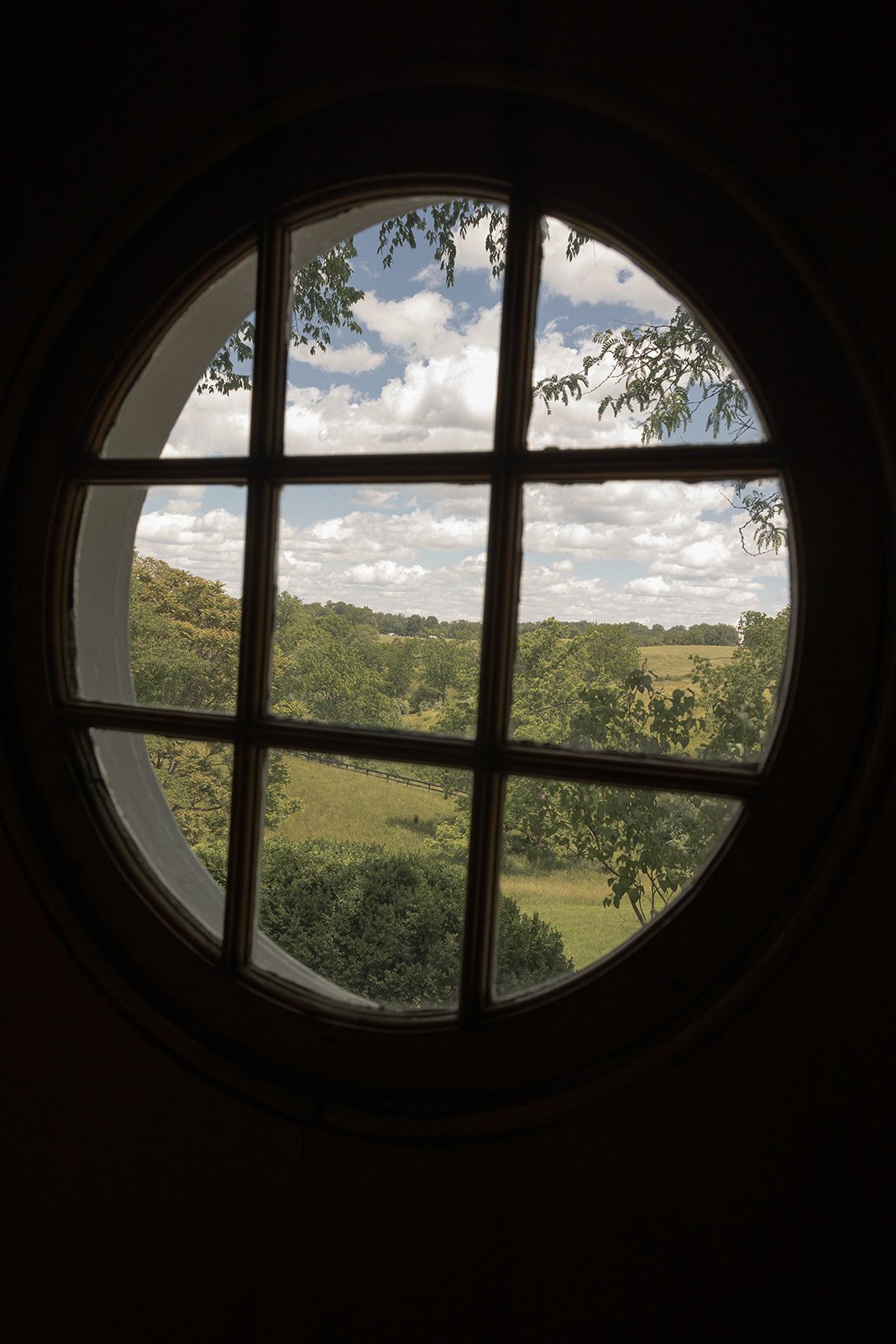 View through a circular window at Goodstone Inn showing the spring landscape outside.