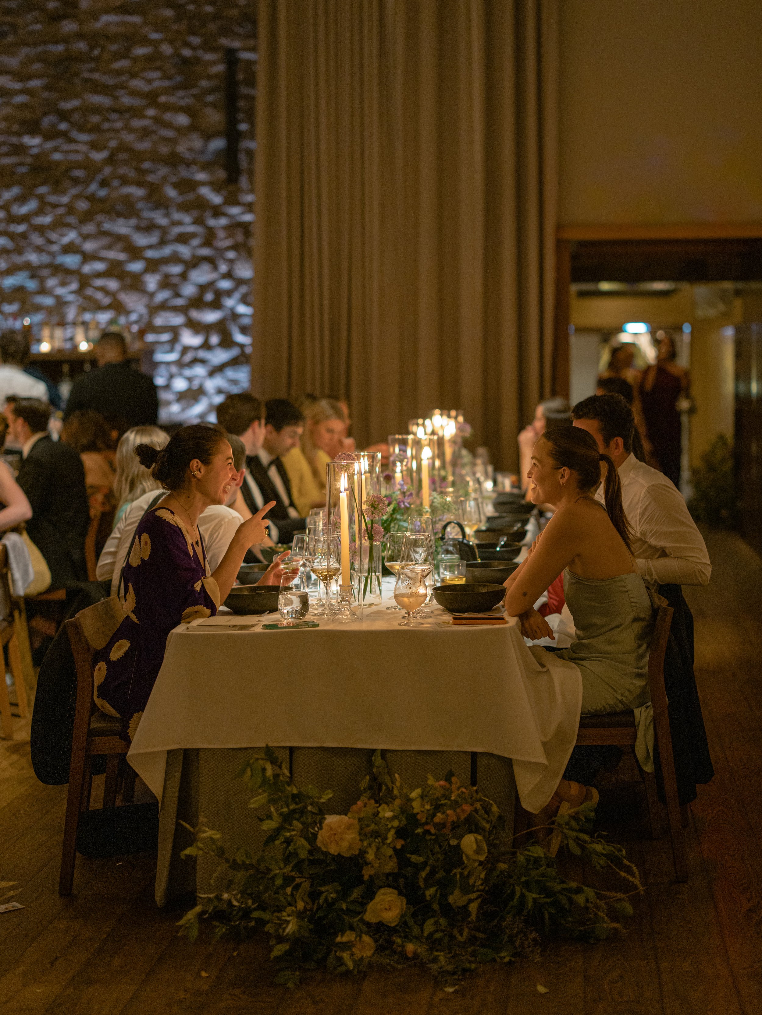 Wide view of guests gathered around the candlelit dinner tables inside Blue Hill at Stone Barns.