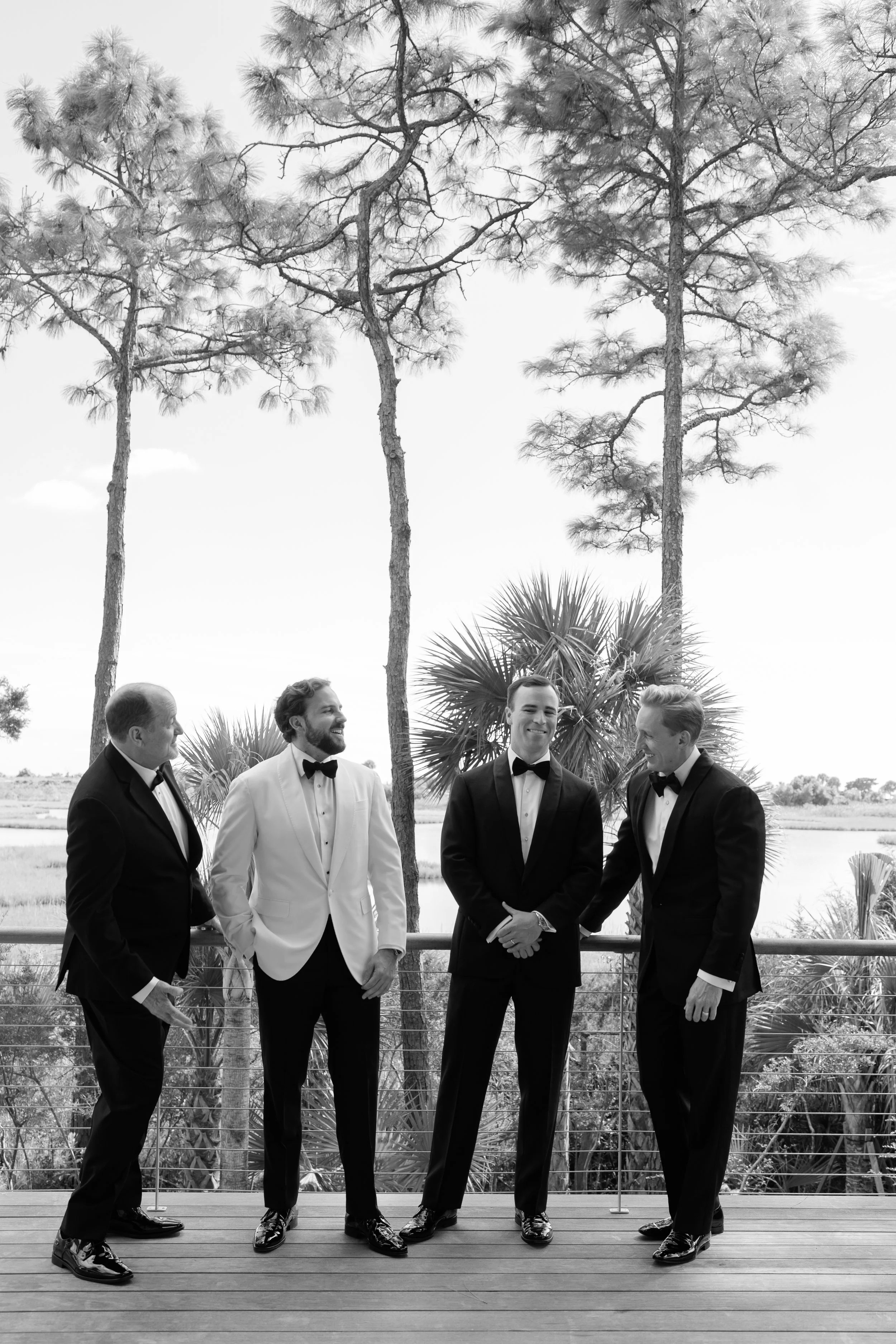Trevor stands with his groomsmen in black-tie attire overlooking the coastal landscape at their private Kiawah Island estate.
