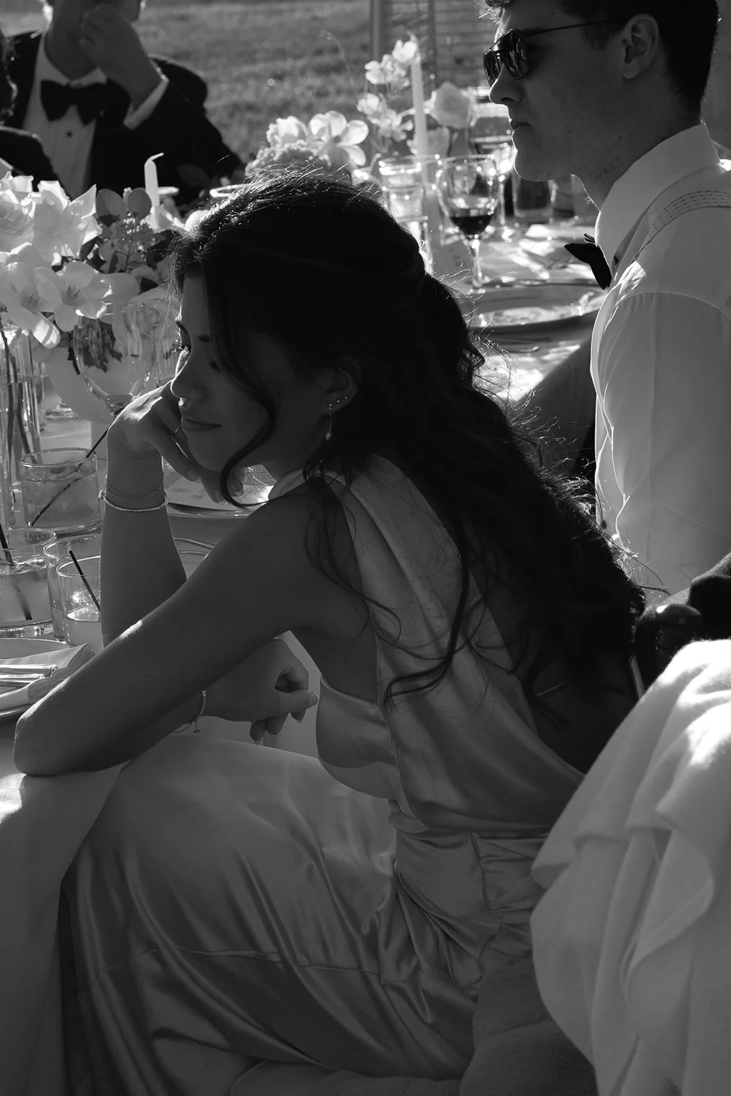 Black-and-white candid of the maid of honor listening to the speeches at a dinner table at Goodstone Inn.