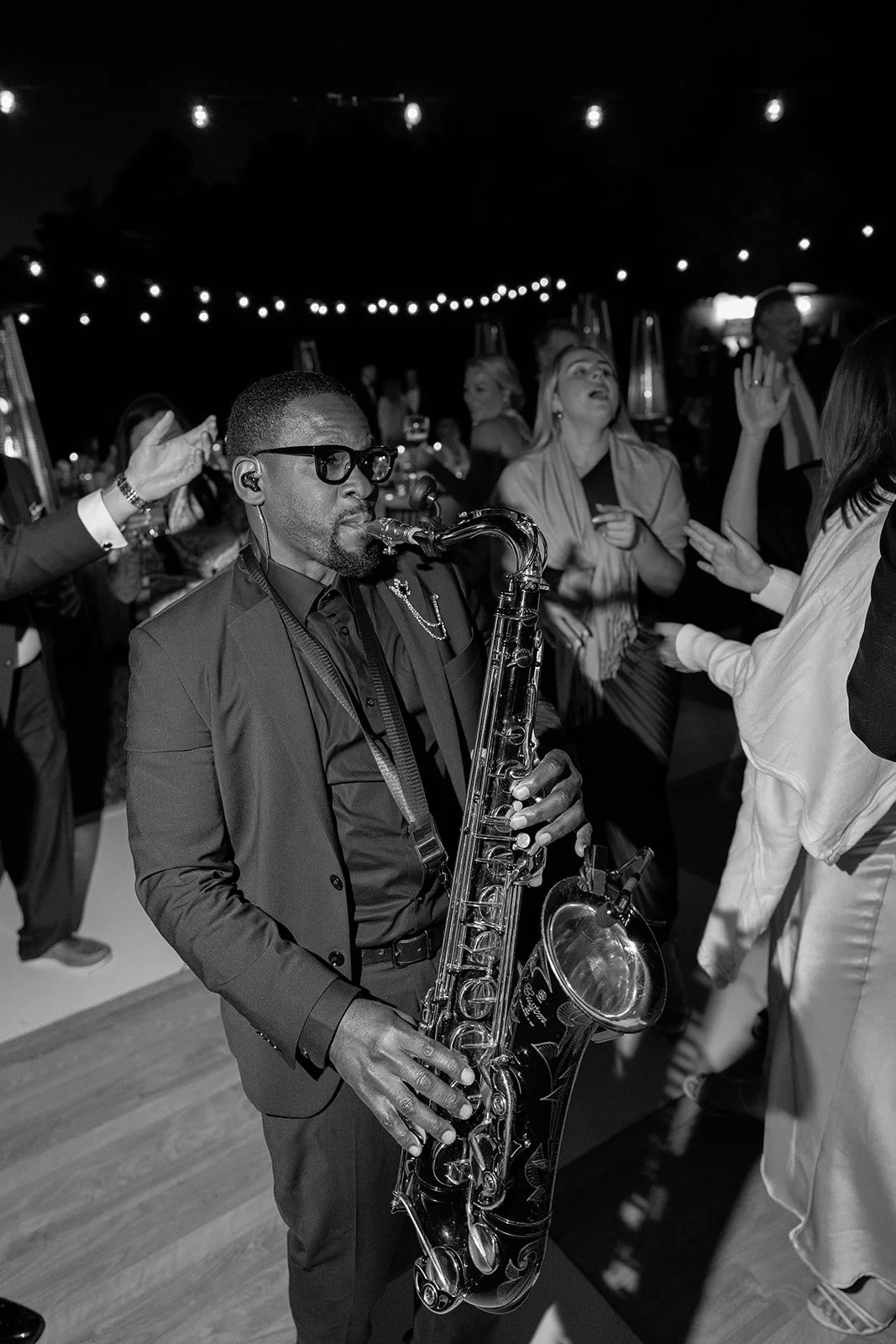 Black-and-white photograph of the saxophonist on the dance floor and wedding guests dancing together during the Goodstone Inn reception.