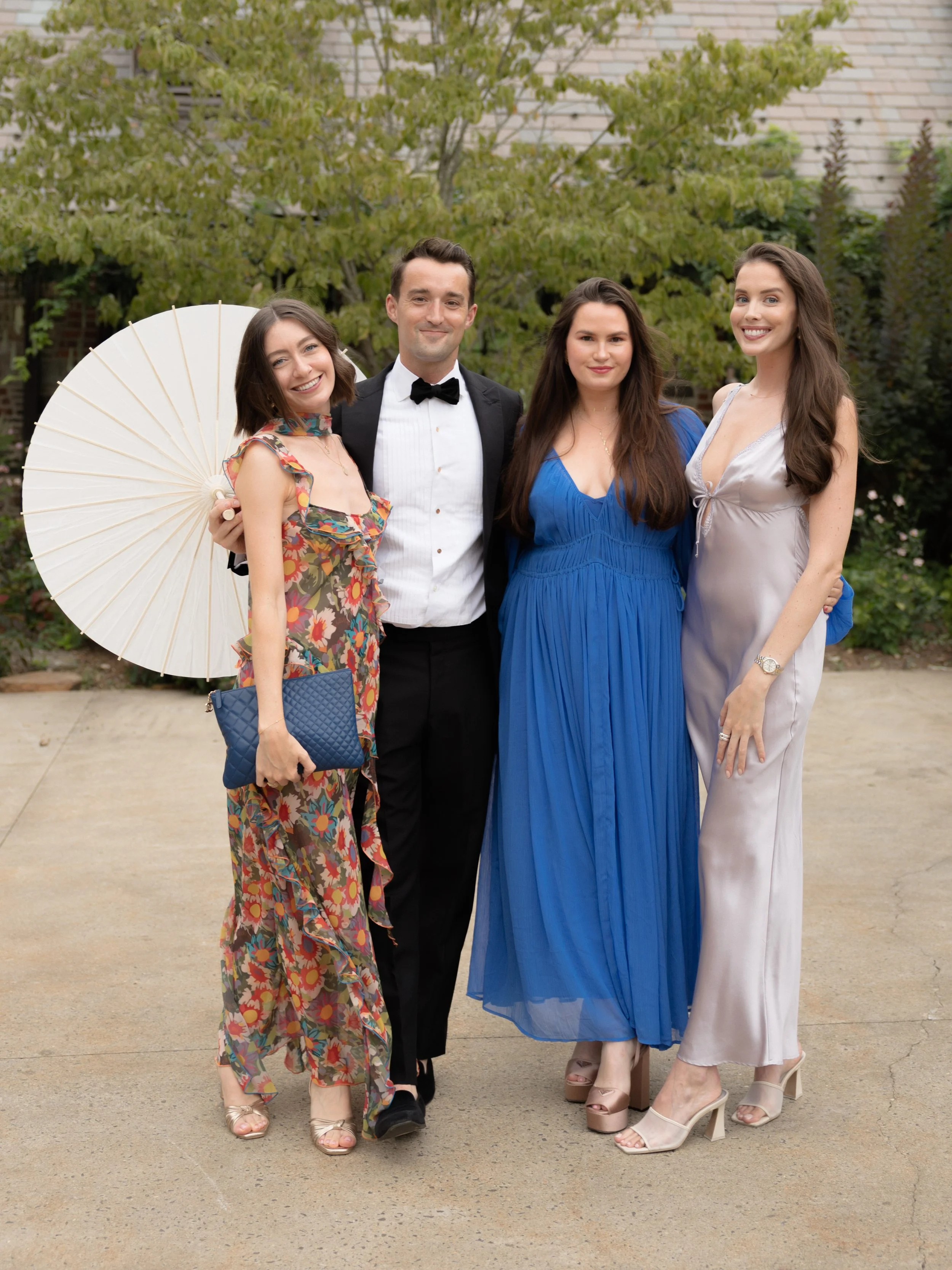 Fashionable guests arrive to the wedding ceremony carrying parasols and dressed in summer florals and colors. 