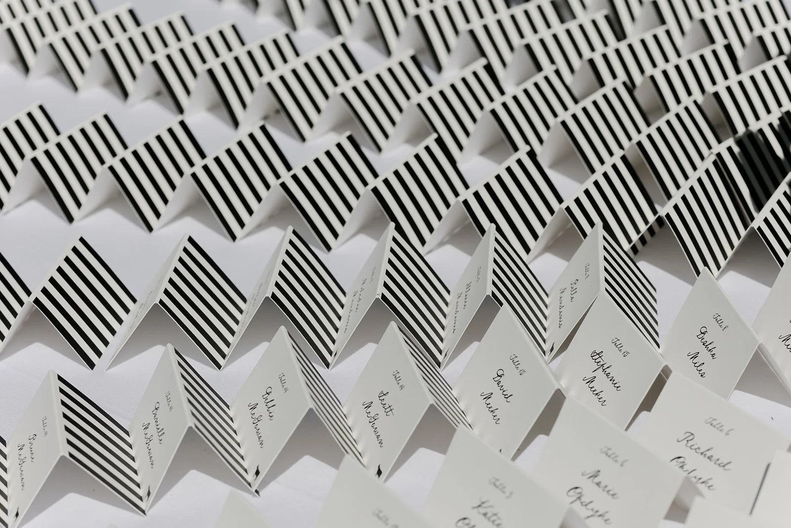 Close overhead view of striped wedding escort cards with handwritten guest names at Goodstone Inn.