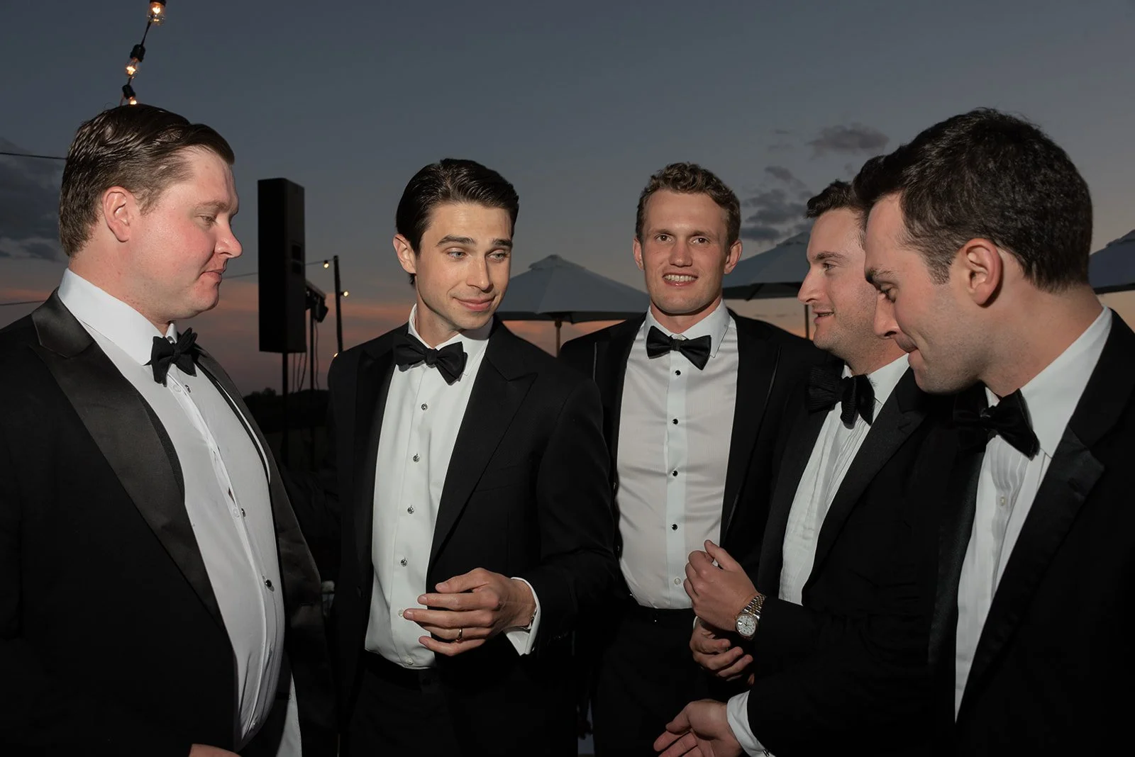 Groom and groomsmen in black tuxedos sharing a candid moment at Goodstone Inn.