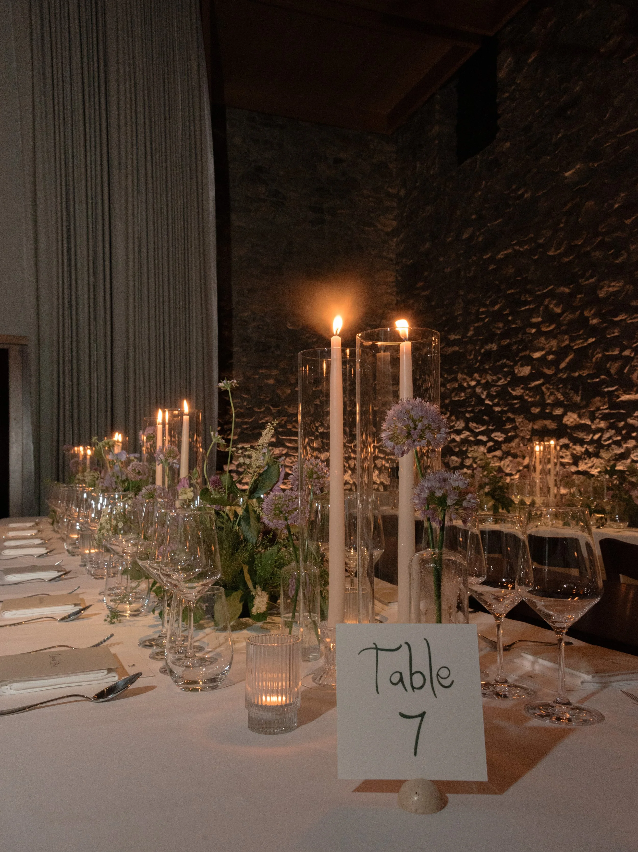 Table number with chic curlicue font surrounded by taper candles and florals at the Blue Hill wedding reception.