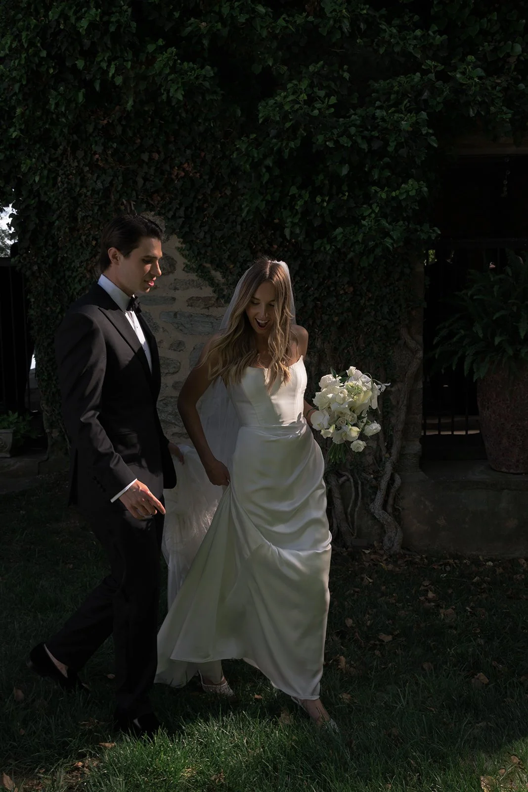 Bride and groom standing together in the gardens at Goodstone Inn with white flowers and greenery around them.