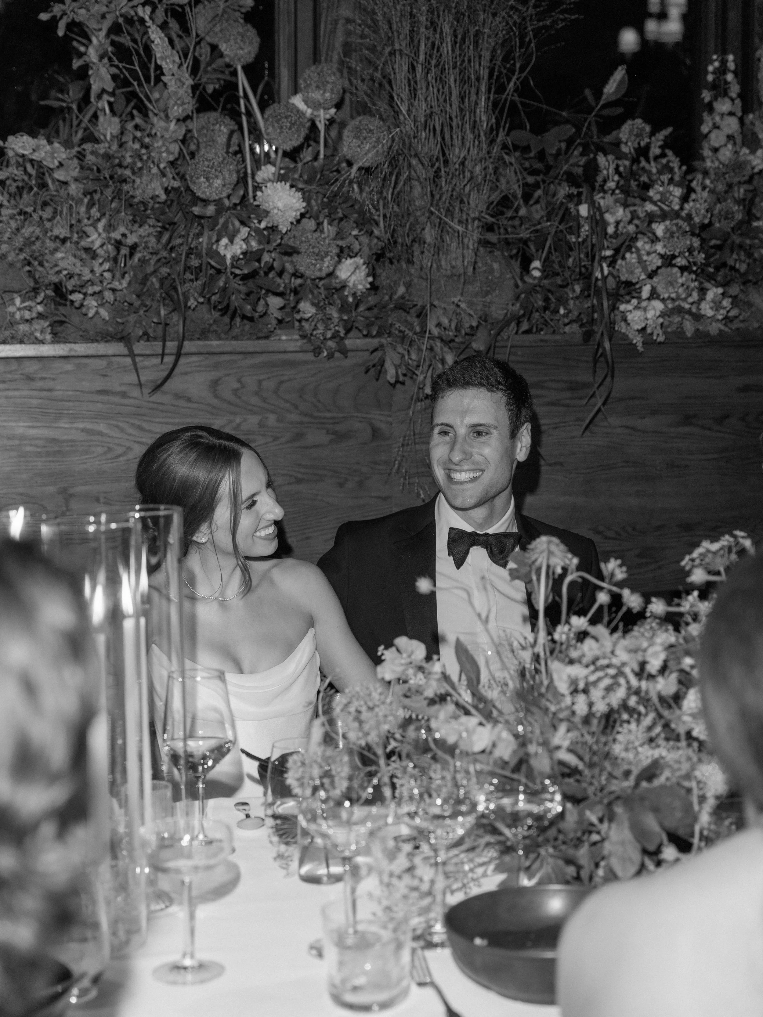 Black-and-white candid of Jennie and Will smiling together during reception speeches.