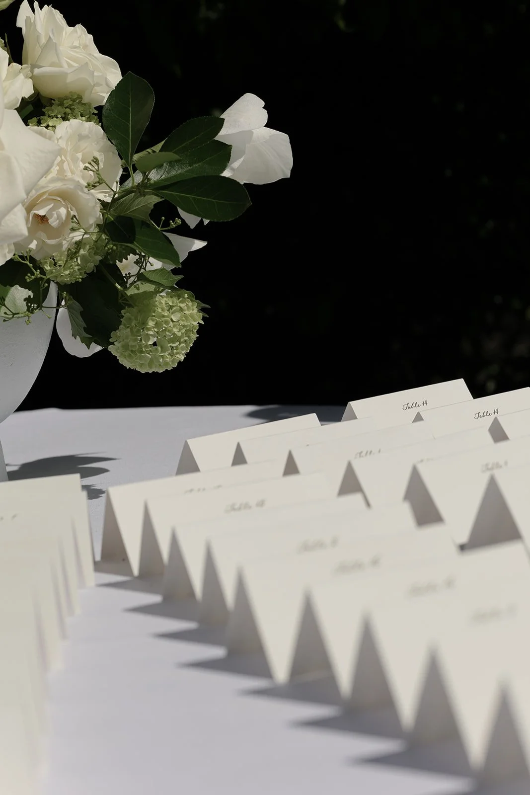 White flower beside rows of escort cards casting geometric shadows in the spring sunlight at Goodstone Inn.