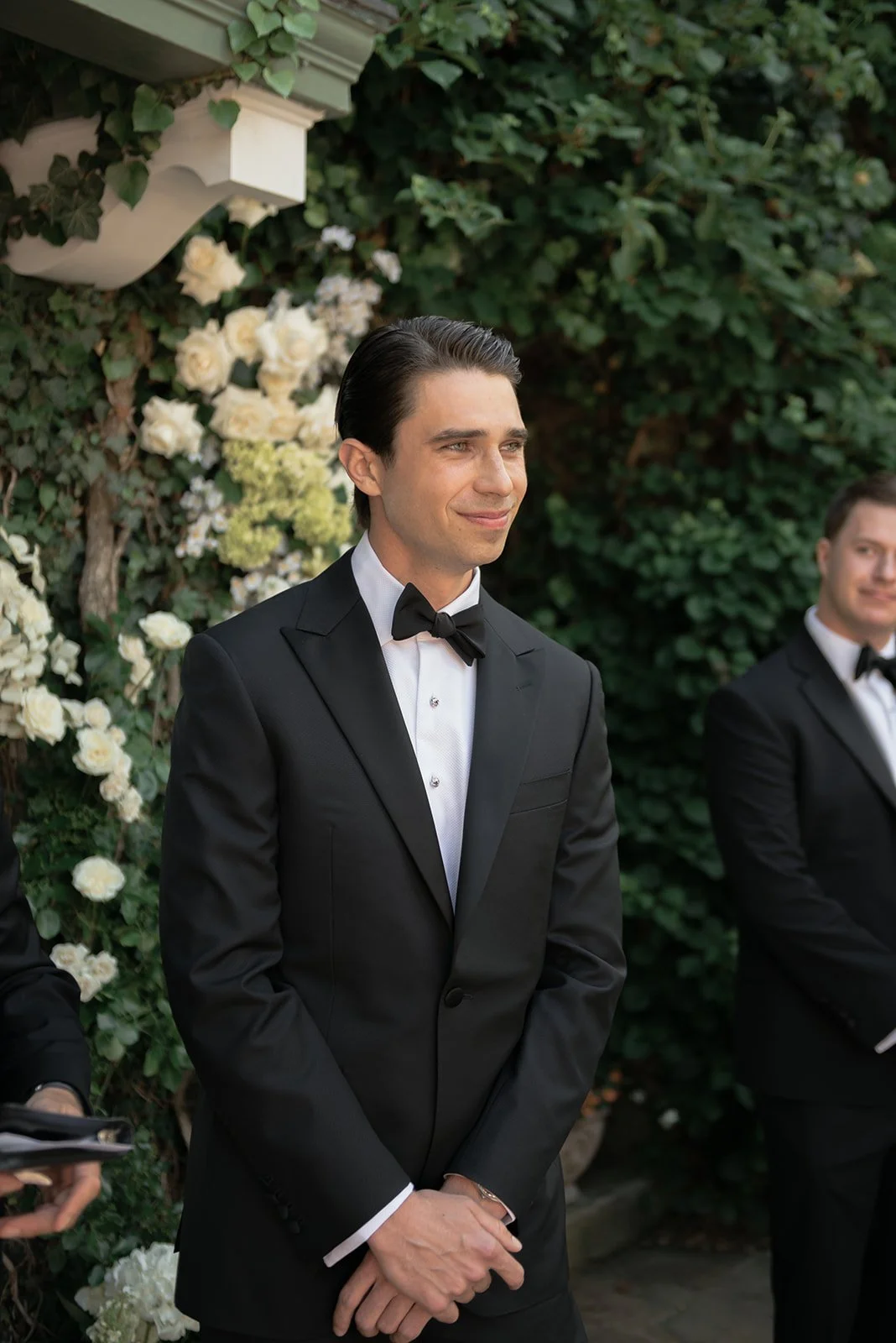 Groom smiling in a black tuxedo during the ceremony at Goodstone Inn.