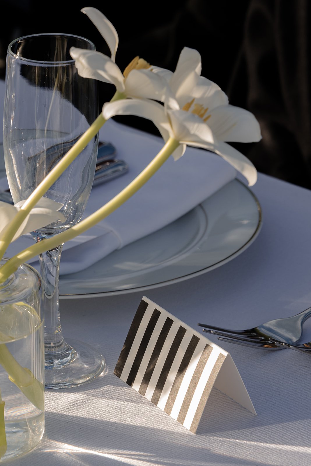 White flower and striped wedding escort card arranged on a place setting at Goodstone Inn in Virginia.