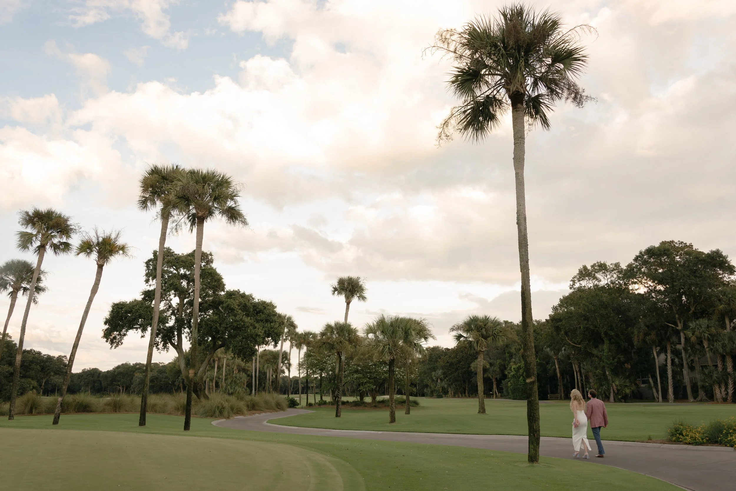 During their Welcome Party, Katie and Trevor walk beneath palm trees across the coastal grounds of the Turtle Point Clubhouse on Kiawah Island.
