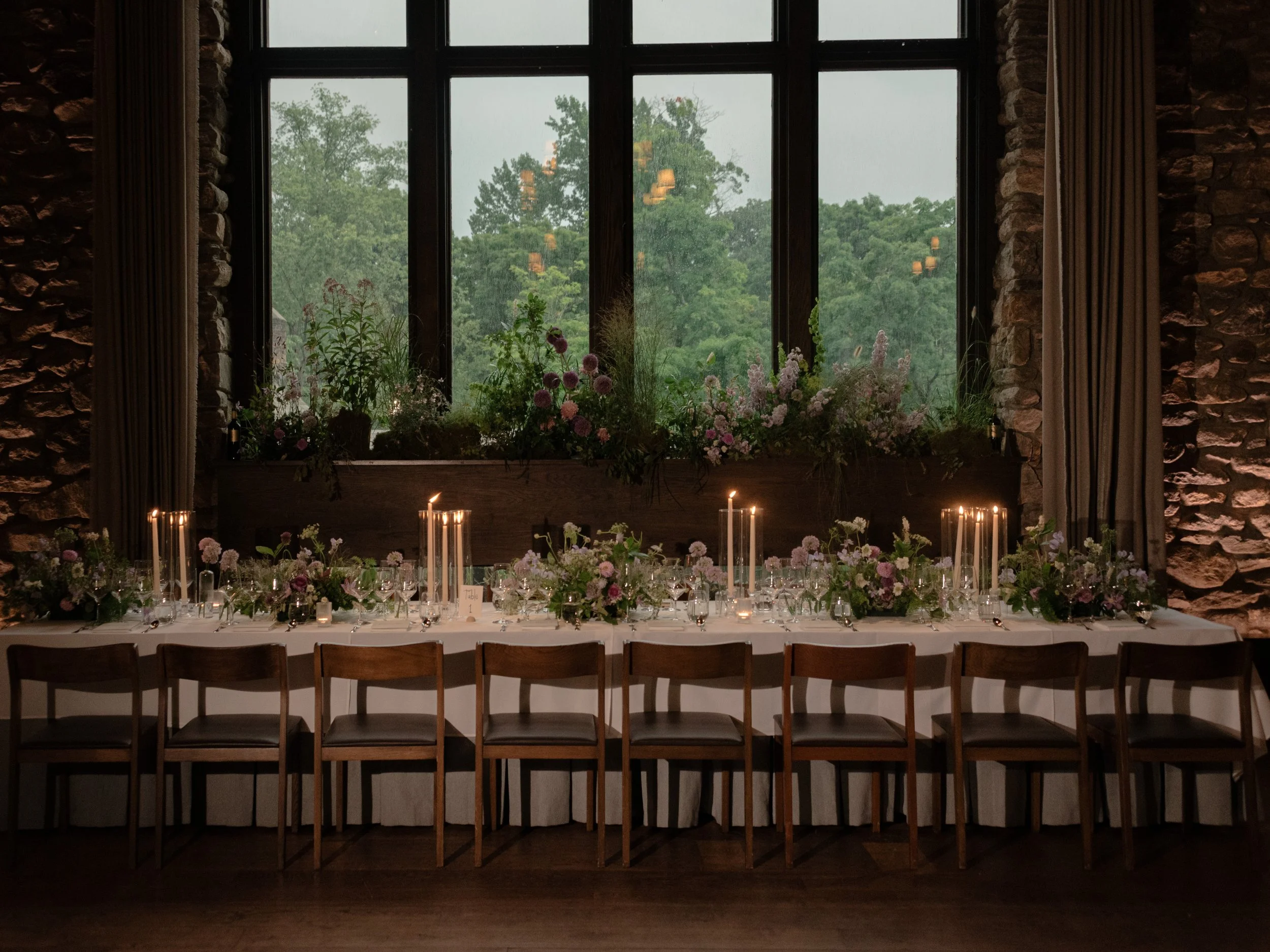 Reception table framed by the large windows overlooking the summer landscape at Blue Hill at Stone Barns.