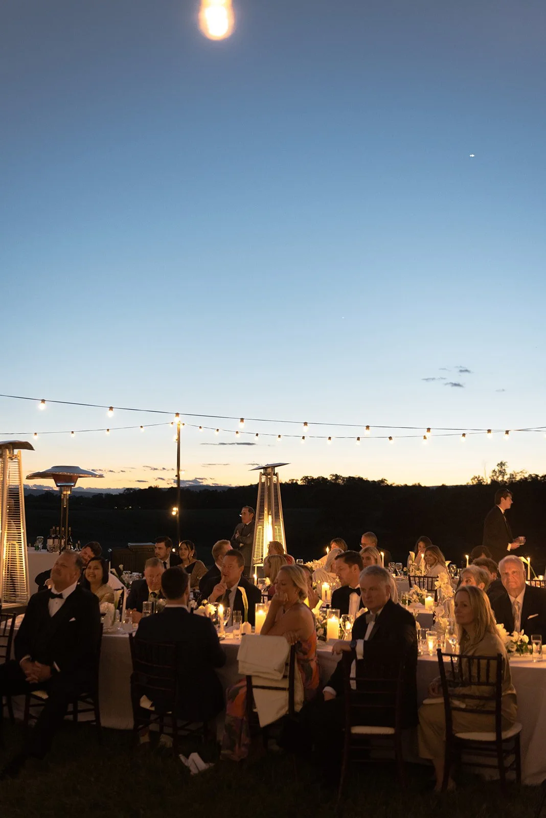 Outdoor Goodstone Inn wedding reception glowing beneath string lights after sunset.