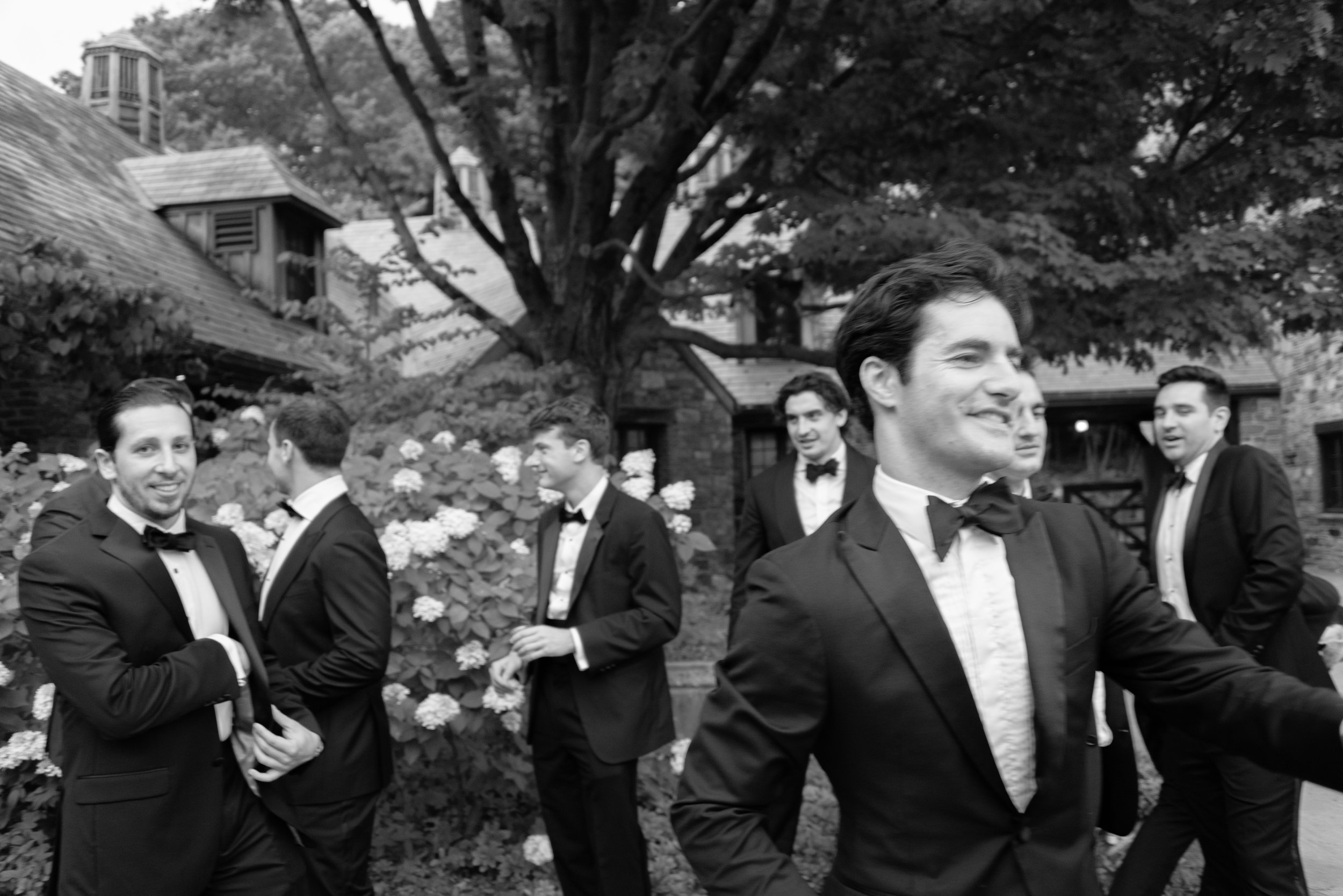 Wedding guests in tuxes gather for a large group photo.