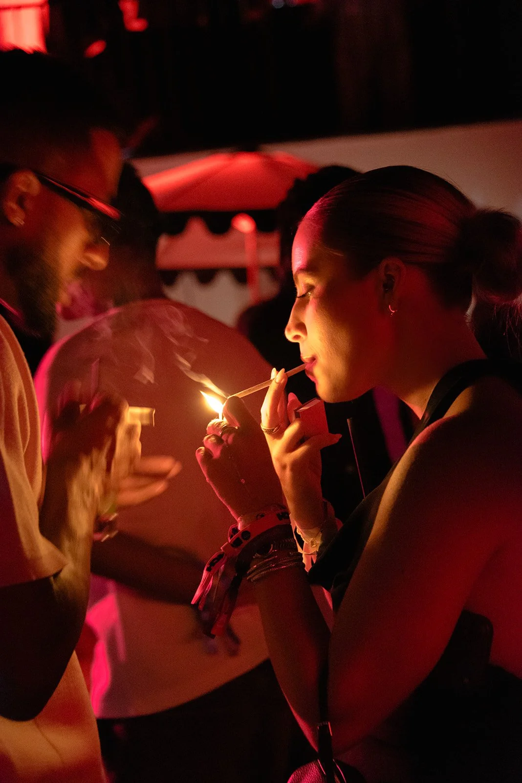Candid photograph of party-goers celebrating under red light during an energetic cocktail party, capturing the atmosphere and movement of the dance floor.