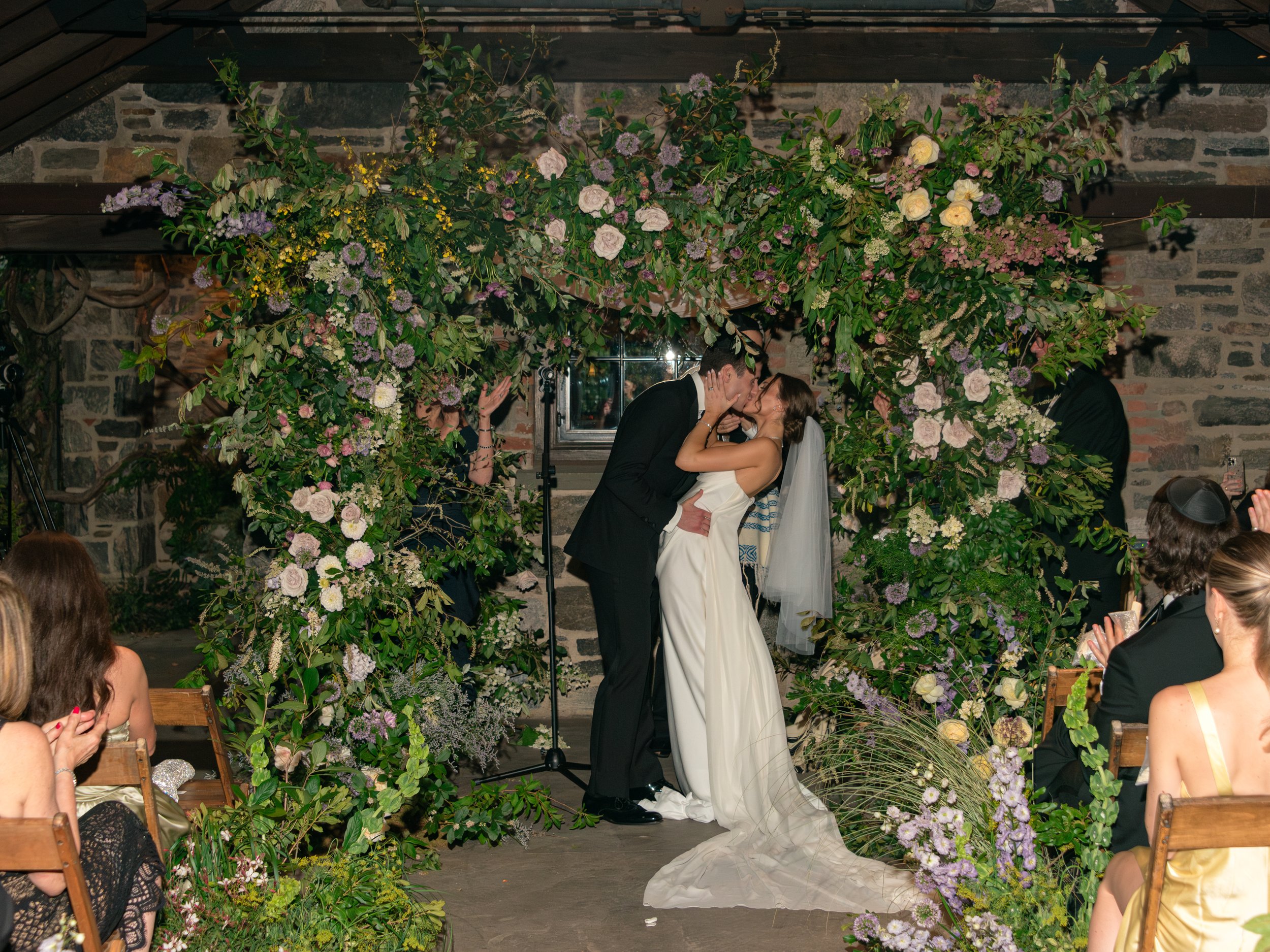 The bride and groom share their first kiss after just smashing the glass.