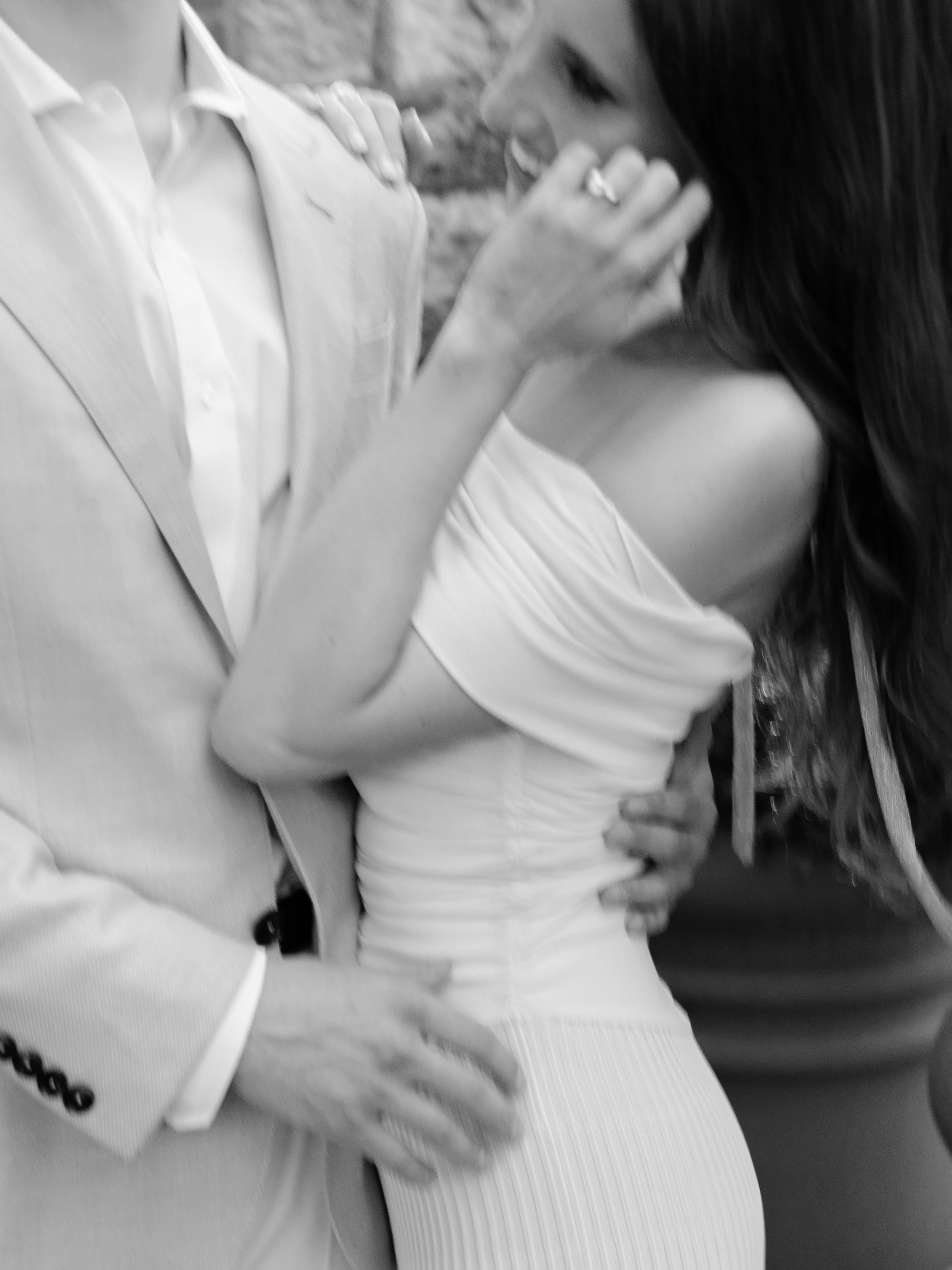 Black-and-white movement close-up of Jennie and Will embracing during their rehearsal dinner portraits.