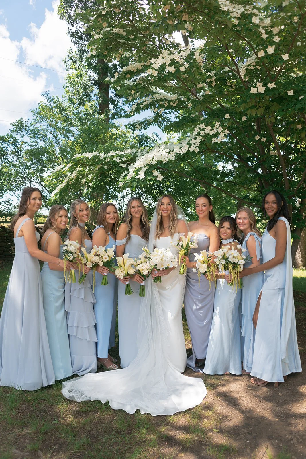 Bride and bridesmaids standing together outdoors in pale blue dresses at Goodstone Inn.