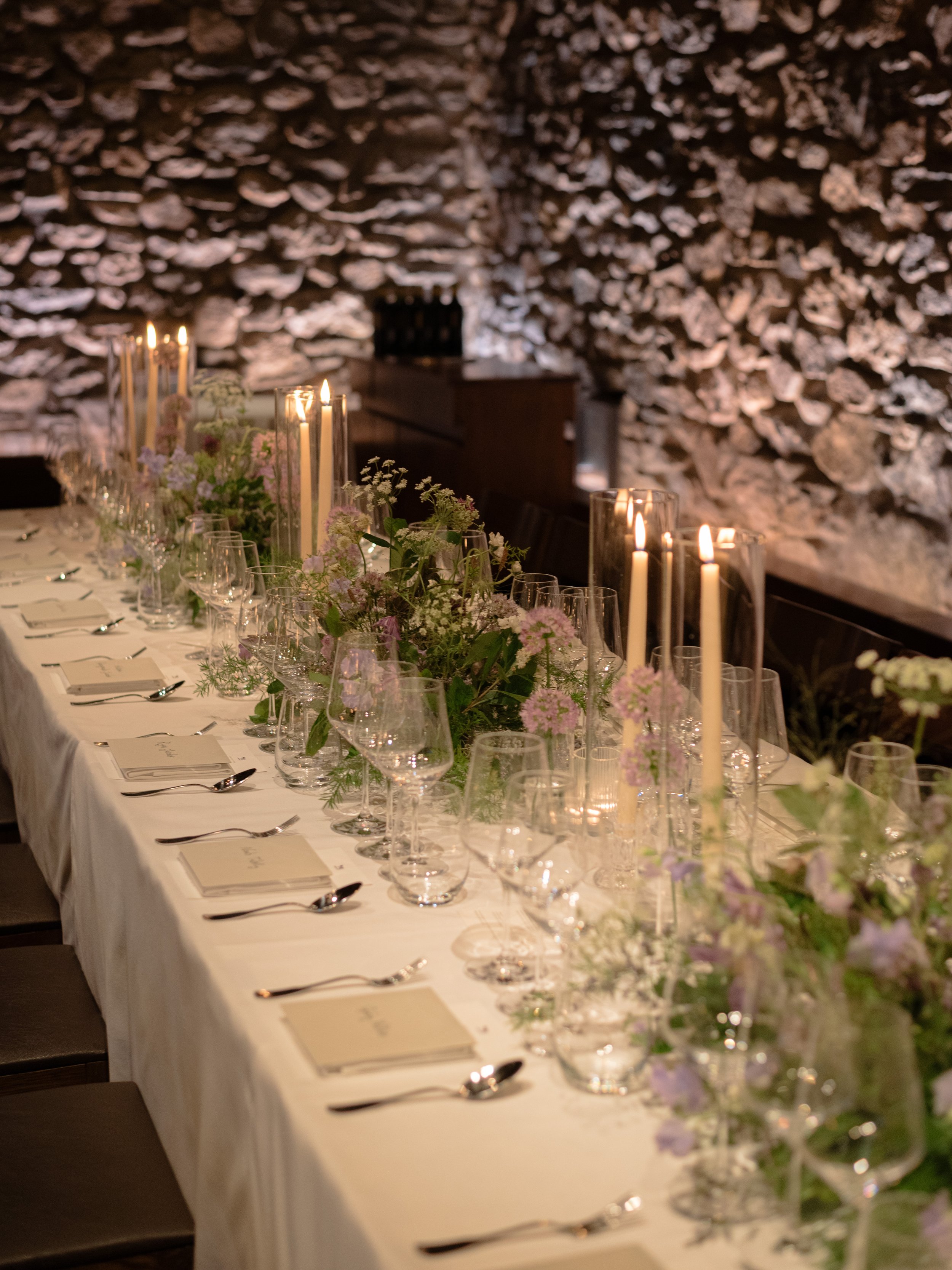 Candlelit reception table stretching along the stone dining room at Blue Hill at Stone Barns.