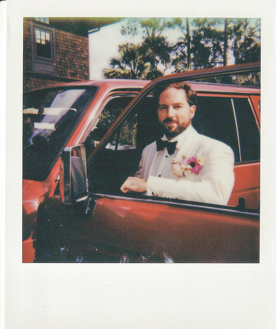 Polaroid portrait of Trevor in a white dinner jacket beside the couple’s vintage red Ford Bronco on Kiawah Island.