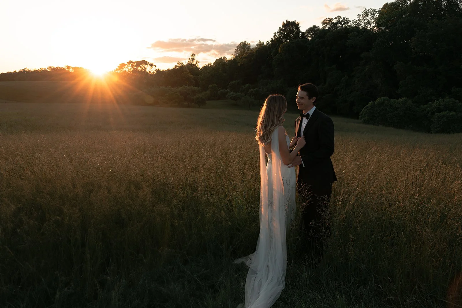 Bride and groom standing together in the Hayfield at sunset during golden hour portraits at Goodstone Inn in Virginia.