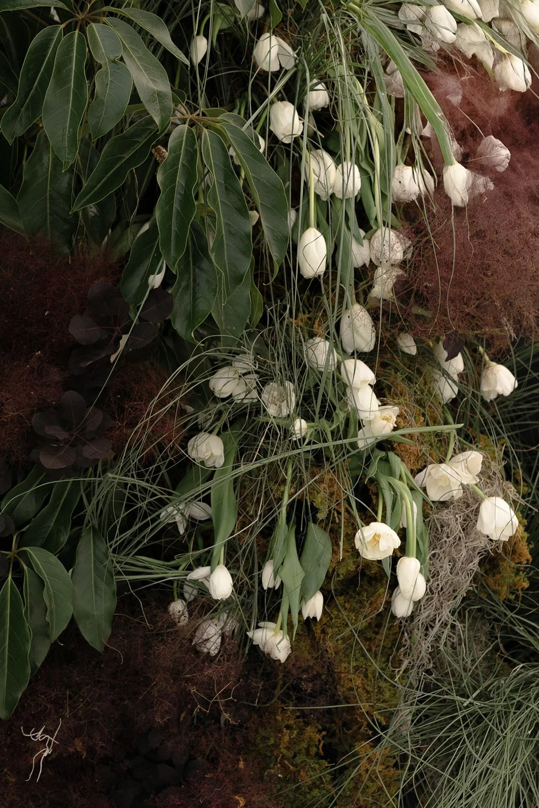 Close-up editorial photograph of white tulip floral arrangements and organic burgundy botanical textures designed for a wedding celebration in Nashville, Tennessee.