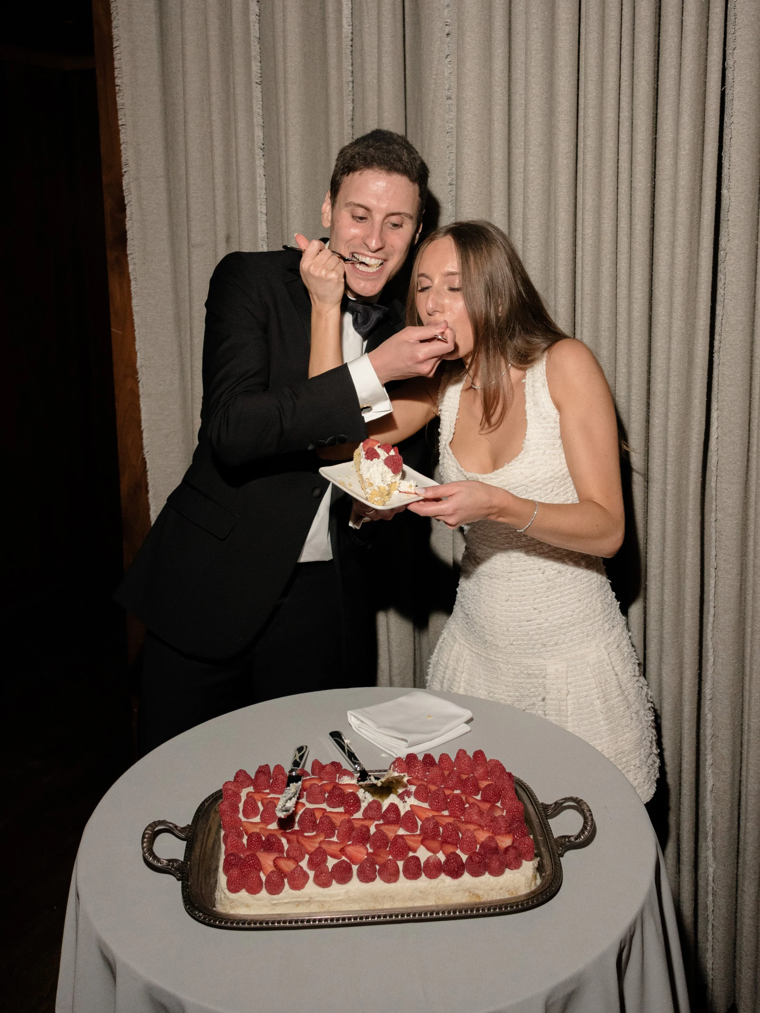 Jennie and Will share cake beside a red berry-topped dessert during their reception.