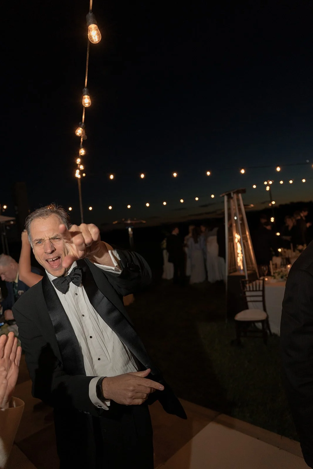 Wedding guest raising a glass during the nighttime reception at Goodstone Inn.