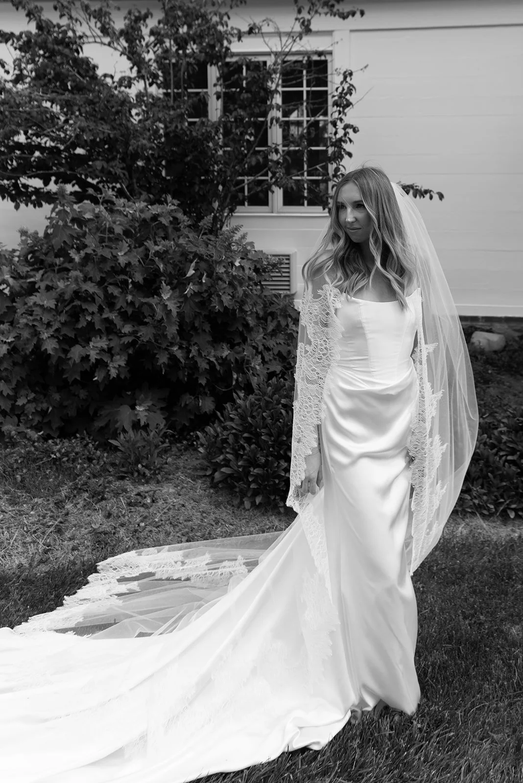 Black-and-white bridal portrait with a cathedral veil blowing in the breeze at Goodstone Inn.