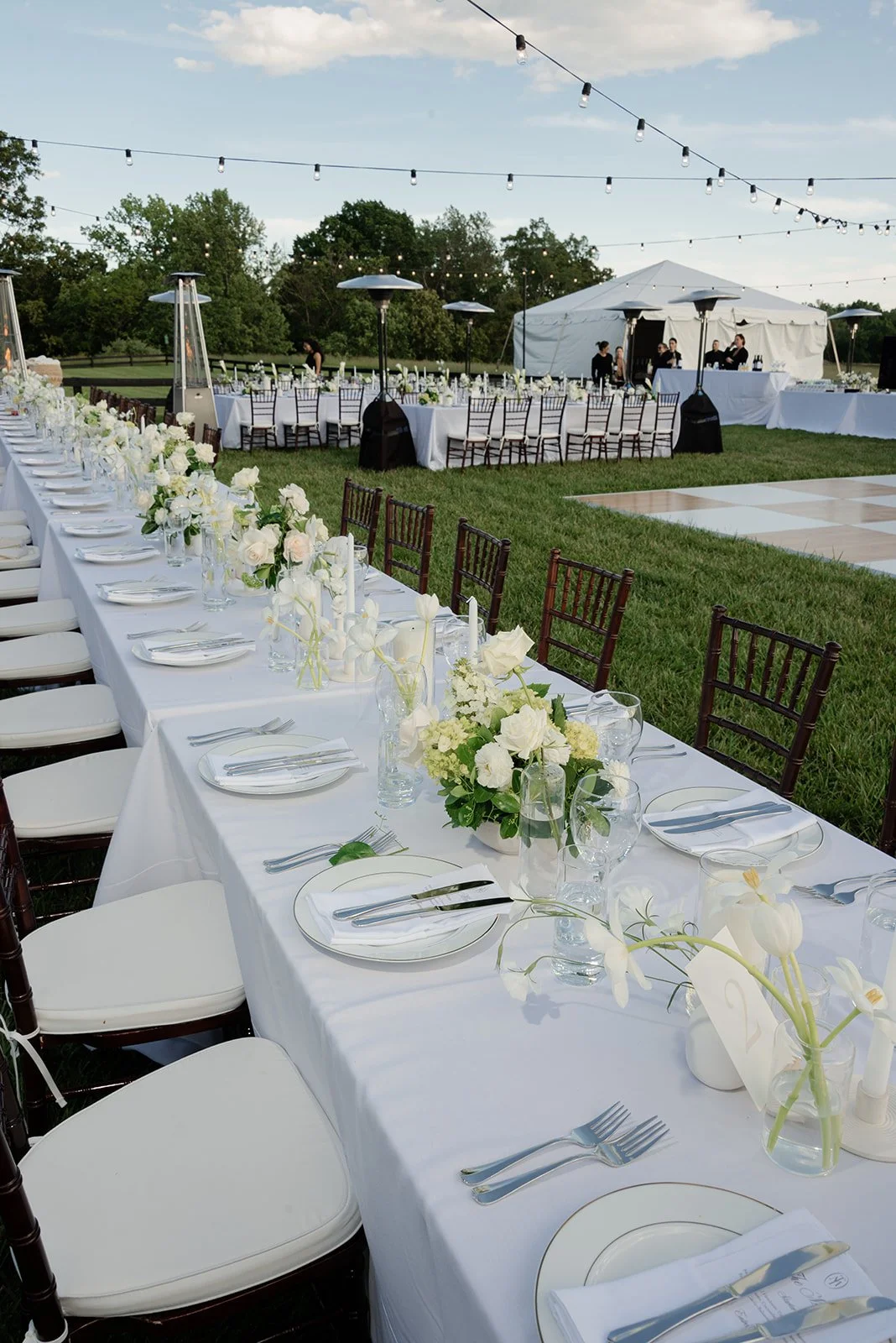 Long white reception table with ivory flowers and candles overlooking the countryside at Goodstone Inn.
