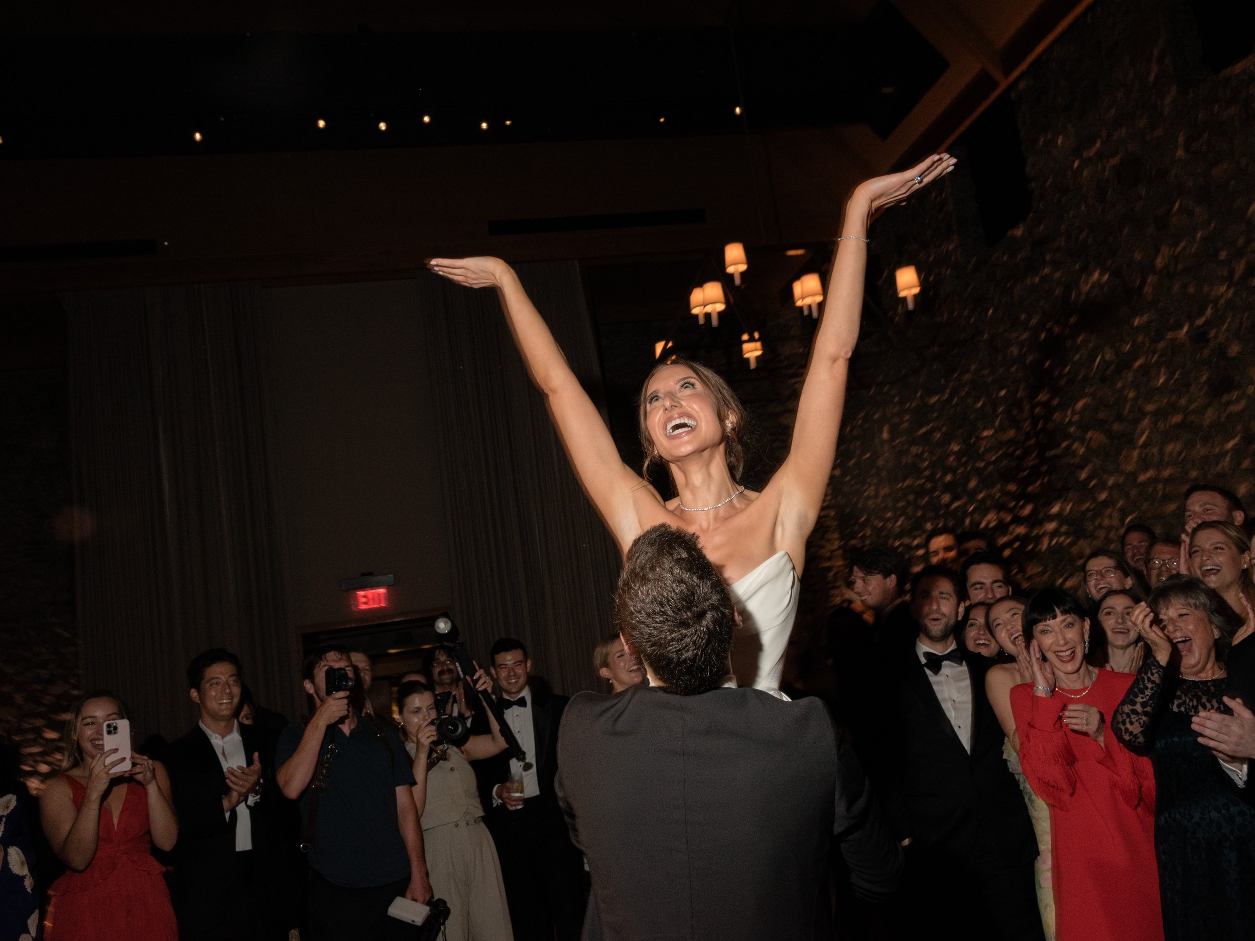 Jennie lifted above the dance floor as guests celebrate during the lively wedding reception.