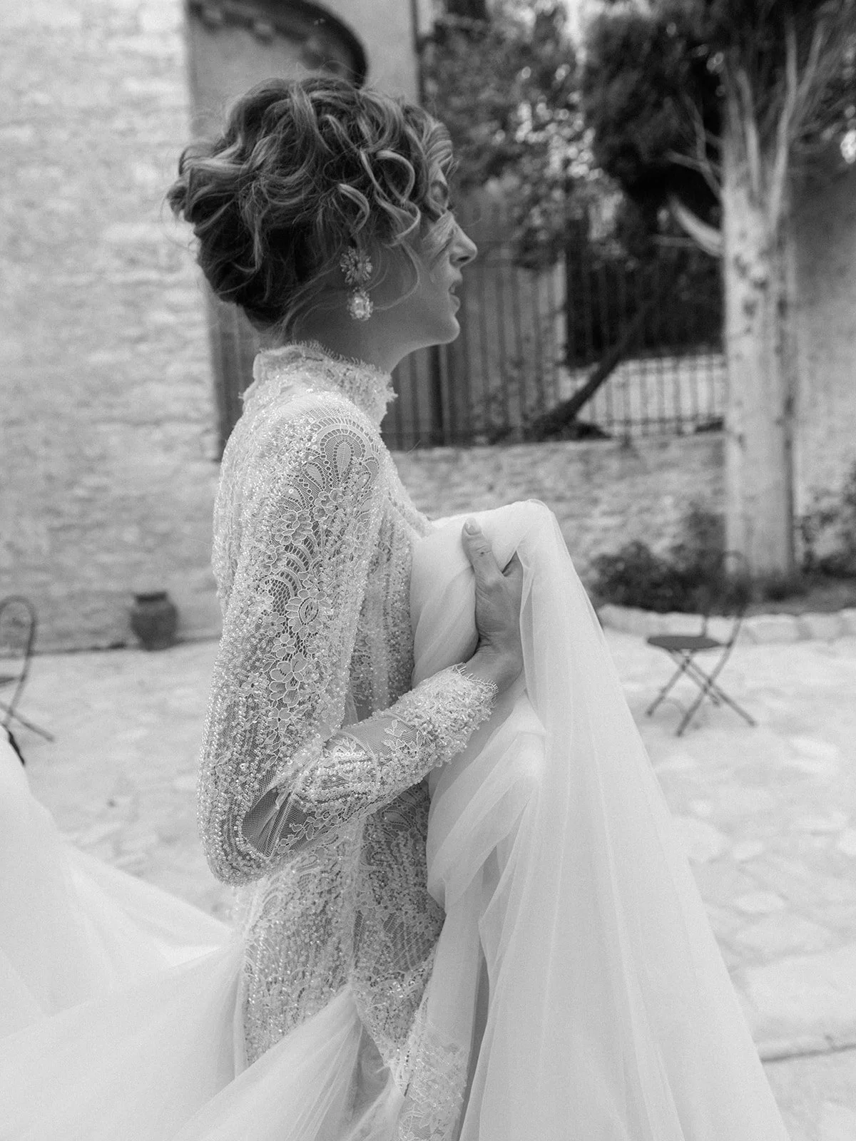 Black-and-white candid of the bride walking through the courtyard of Abbazia San Pietro in Valle in Umbria, Italy